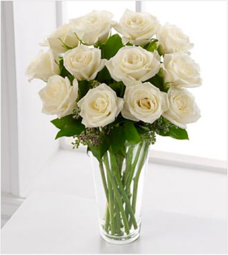 Arrangement of white roses in a clear glass vase on a white surface
