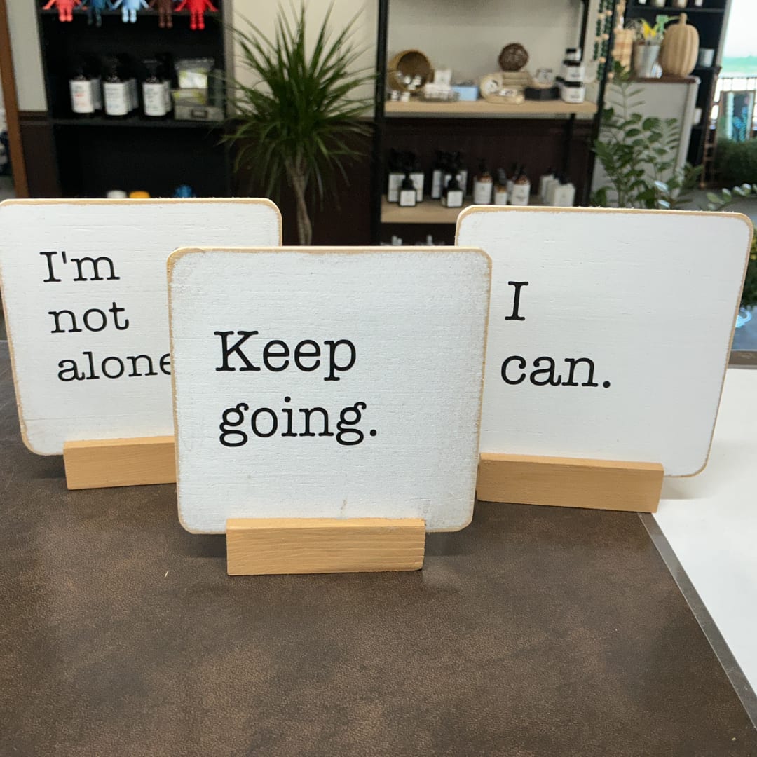 Three wooden signs with motivational text on stands