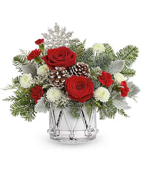 Red roses and white flowers in a clear glass vase with pinecones