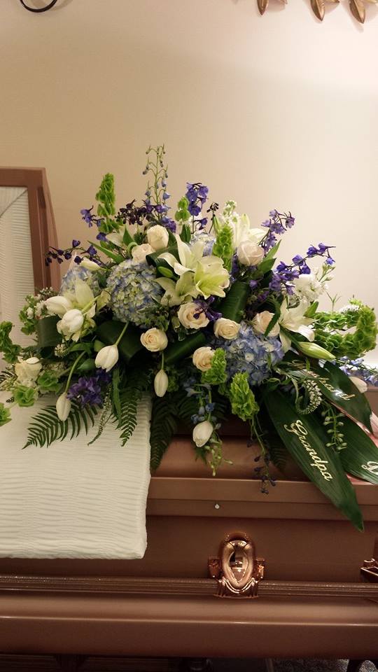 White and blue floral casket spray with purple accents