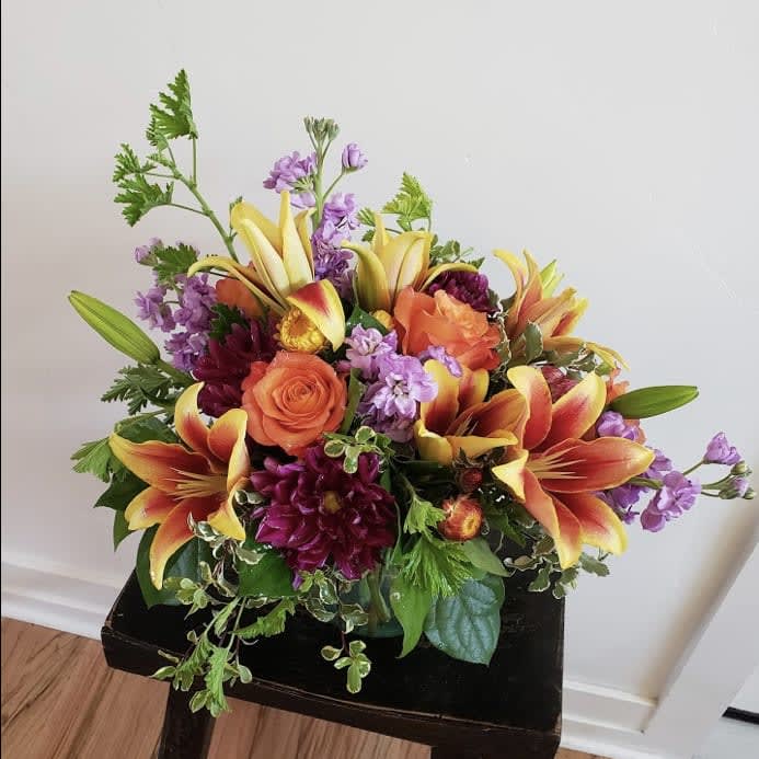 Bouquet of orange roses, lilies, and purple flowers