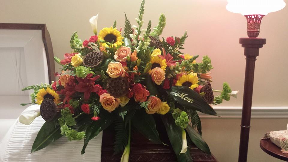 Large mixed floral spray with sunflowers, roses, and lilies in warm colors