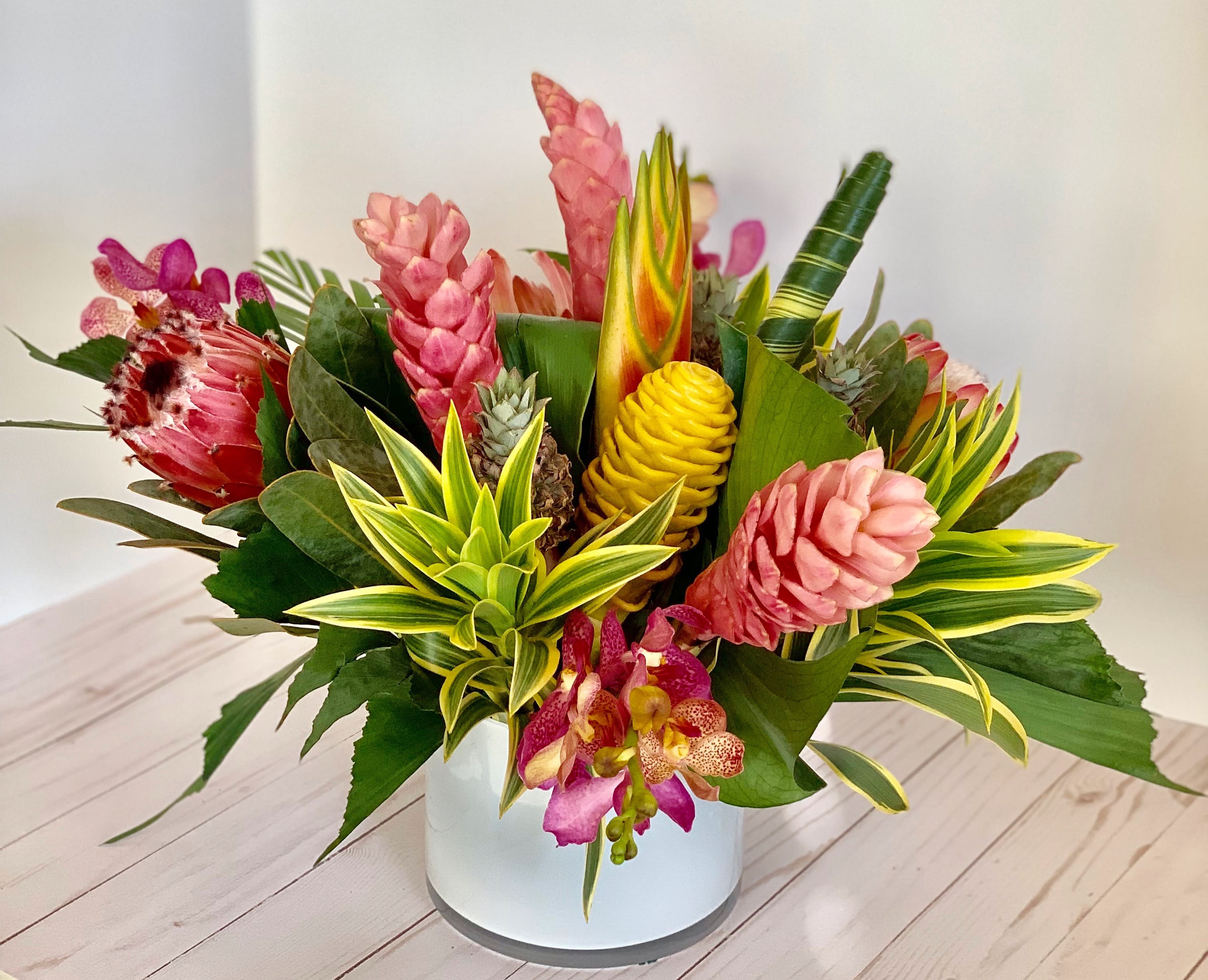Tropical flower arrangement in a white vase with pink and yellow blooms