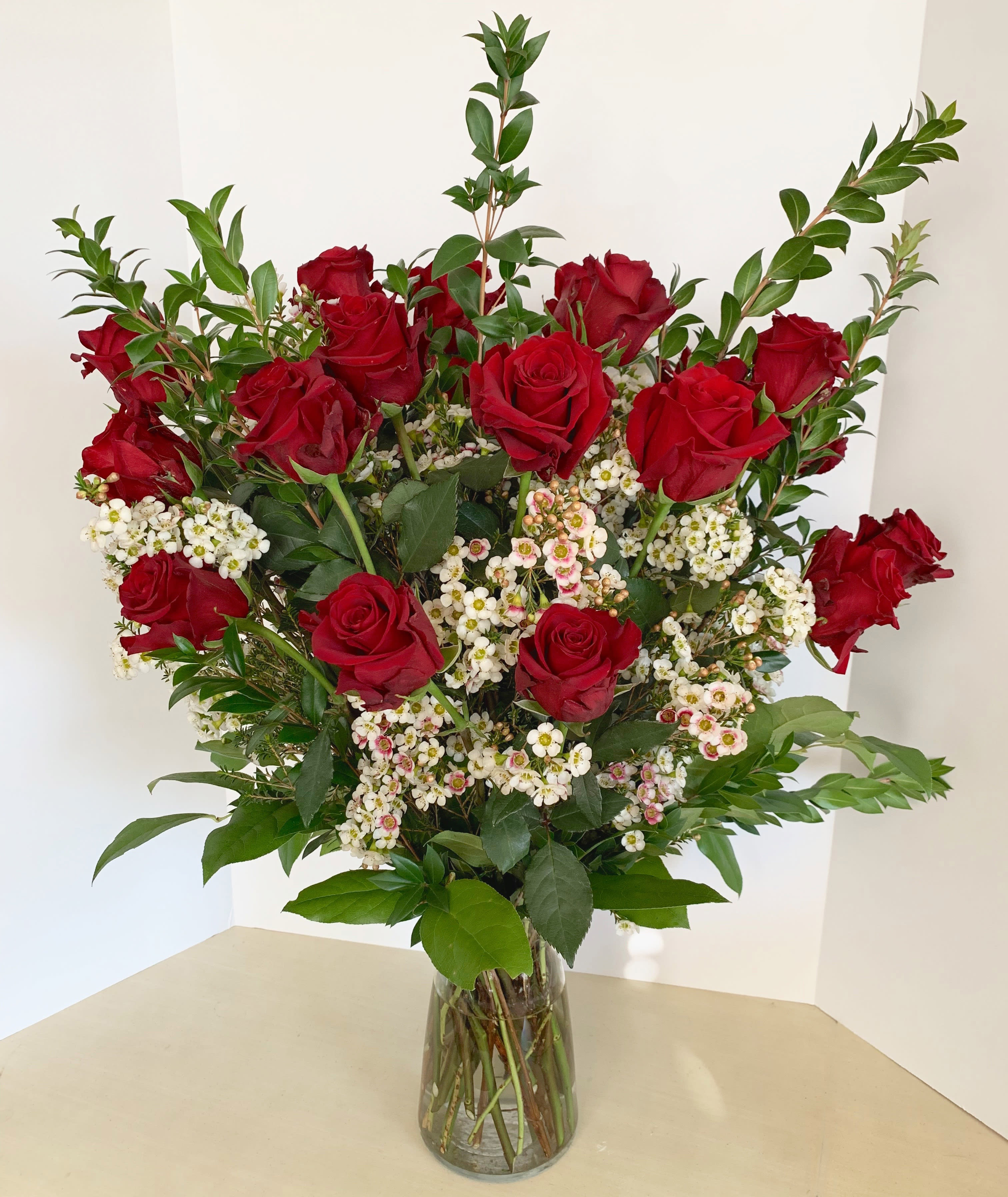 Red roses and white filler flowers in a clear glass vase