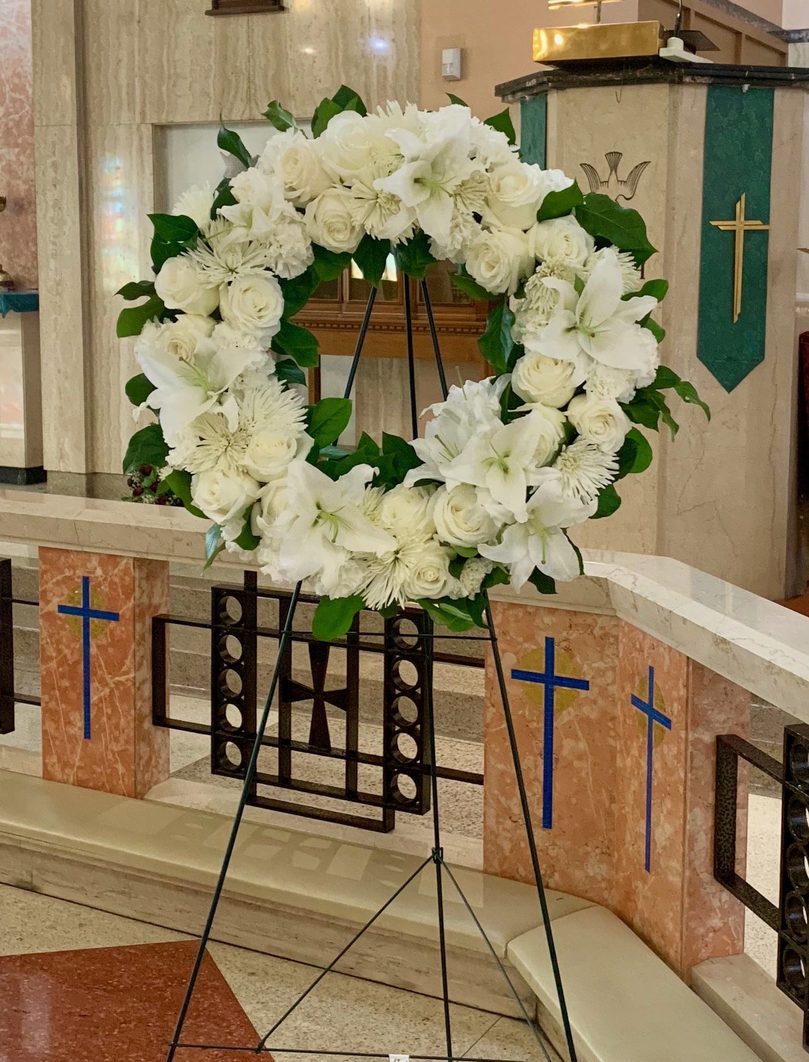 White floral wreath on a stand in a church interior