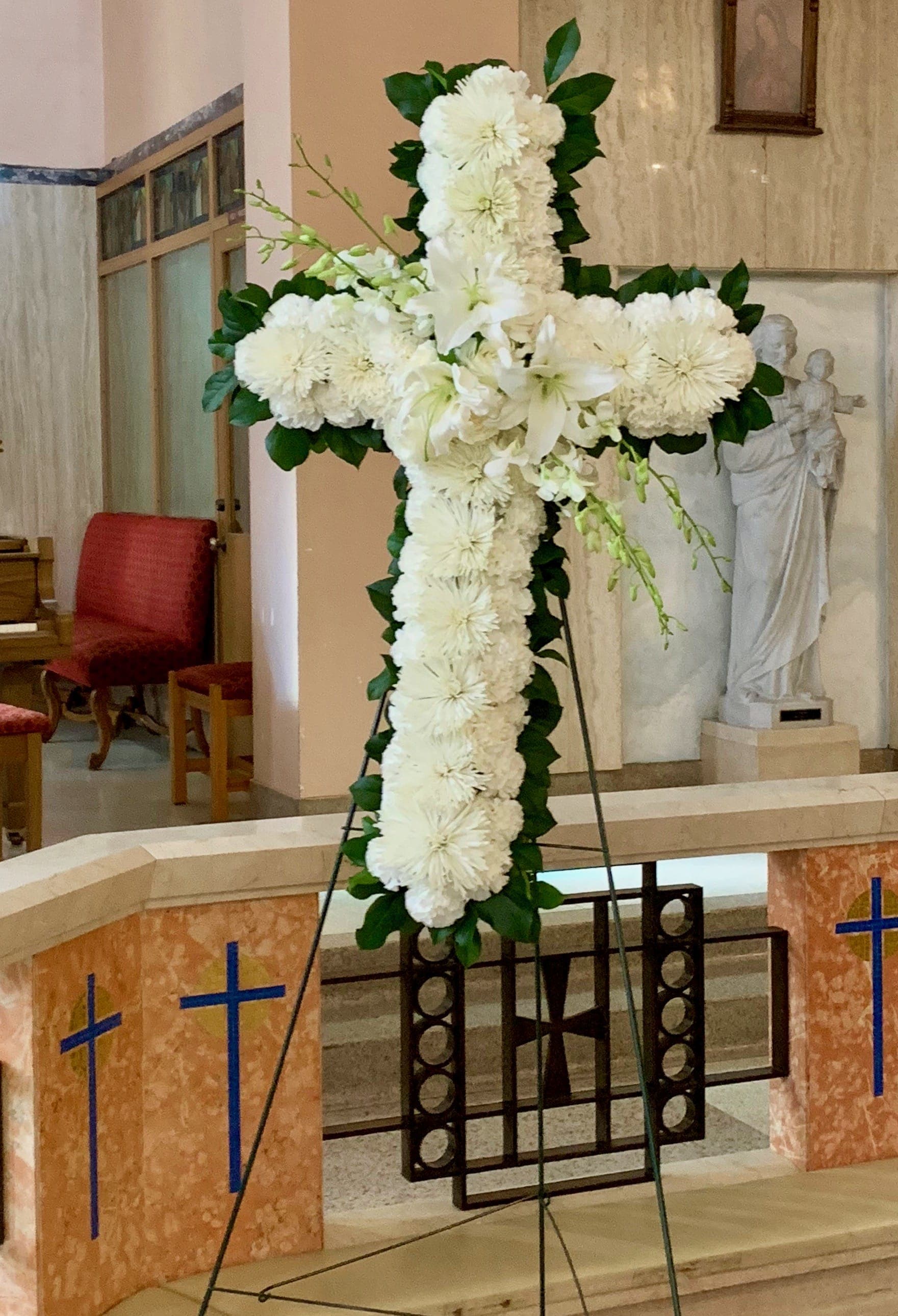 White floral cross on an easel in a church interior
