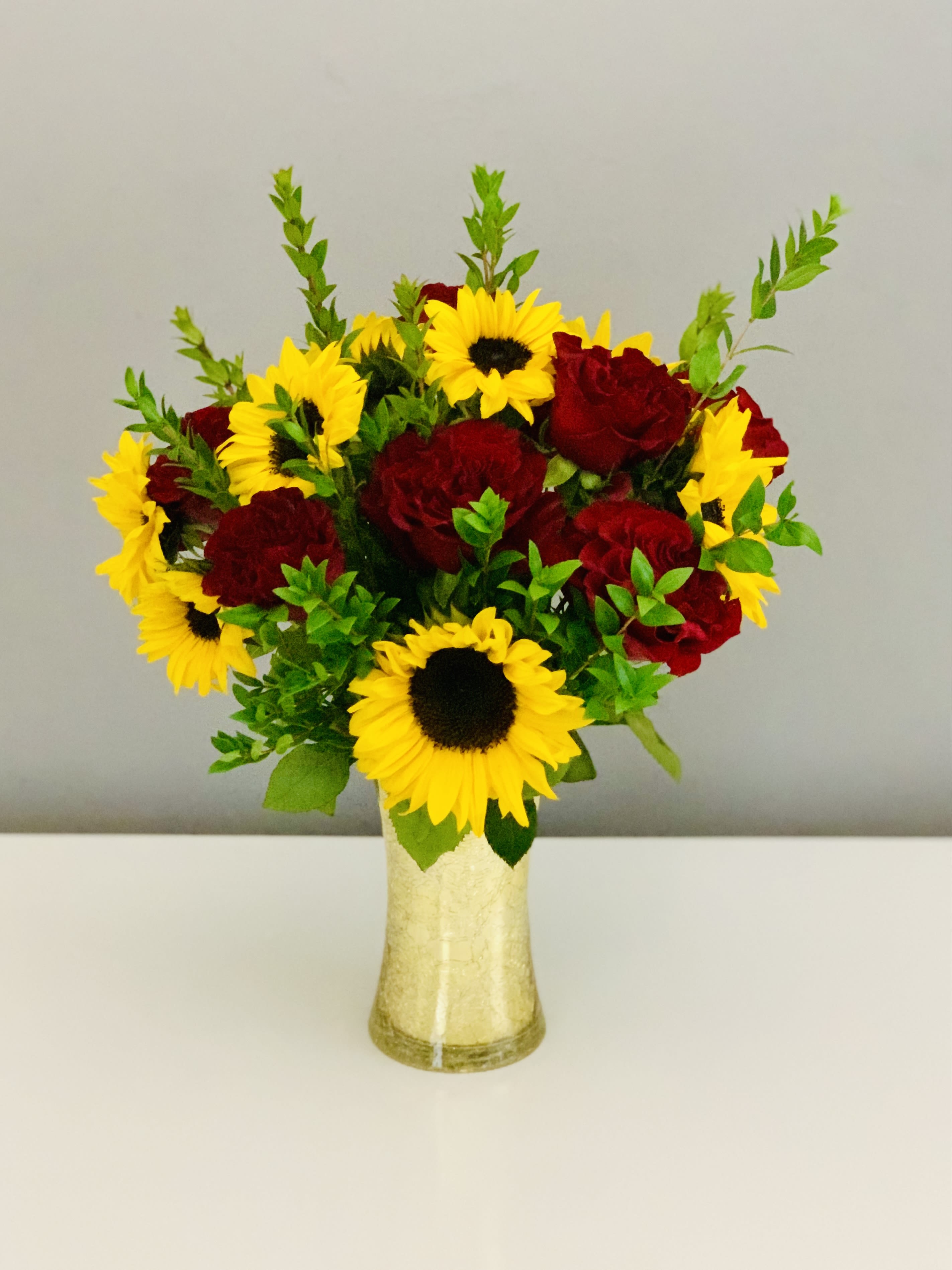 Bouquet of red roses and yellow sunflowers in a gold vase