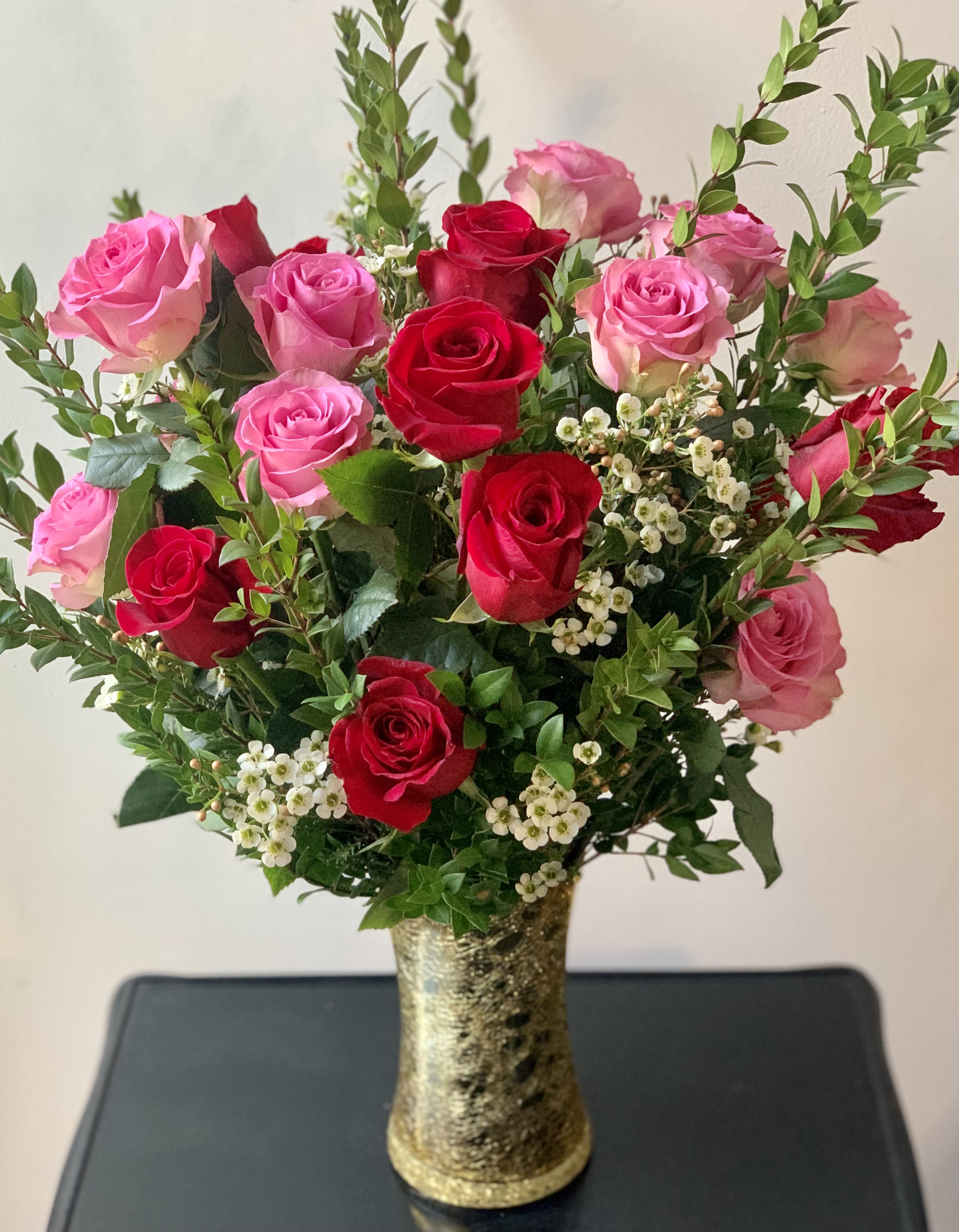 Pink and red roses arranged in a gold vase