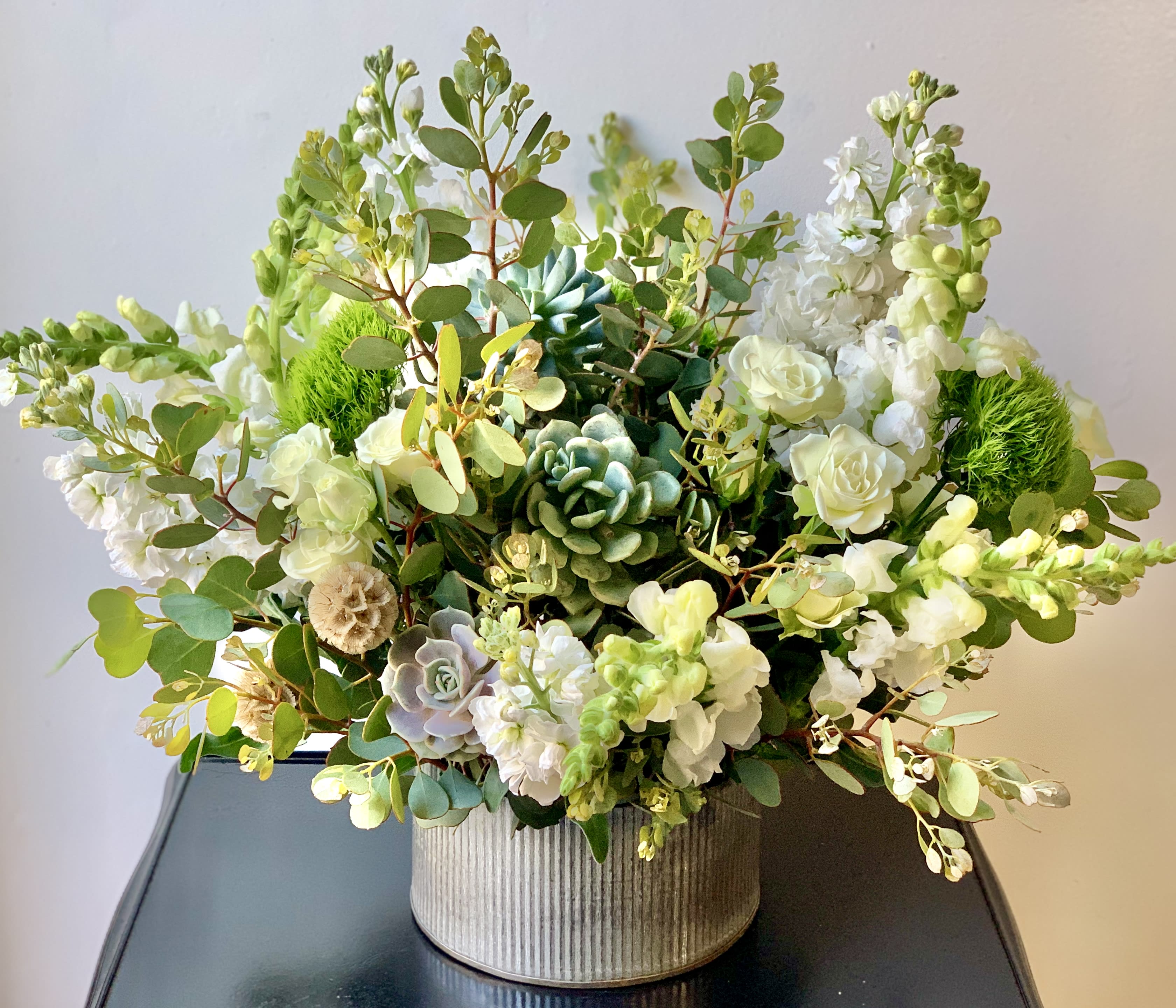 White floral arrangement with succulents in a ribbed container