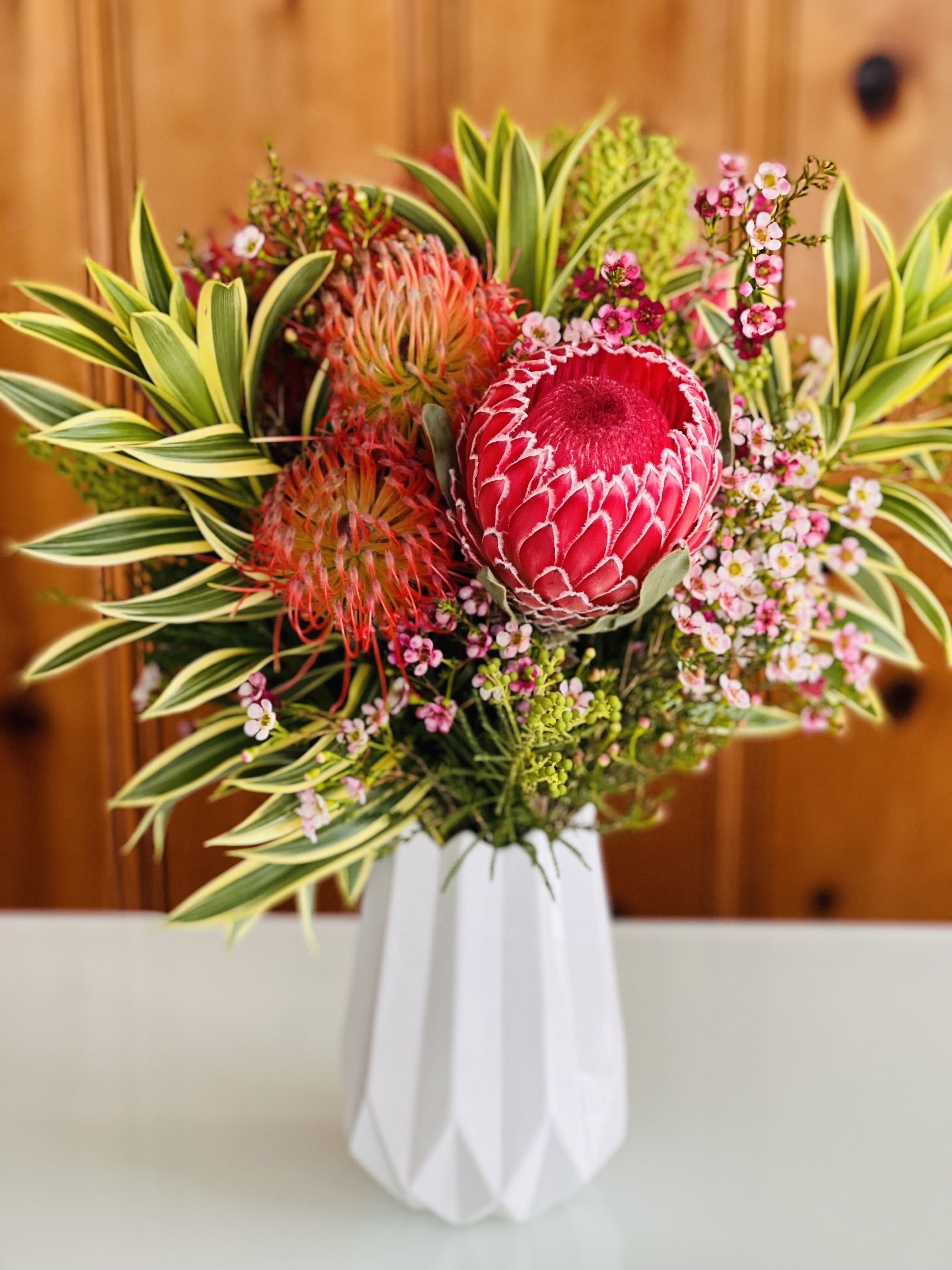 Tropical bouquet with pink protea in a white vase