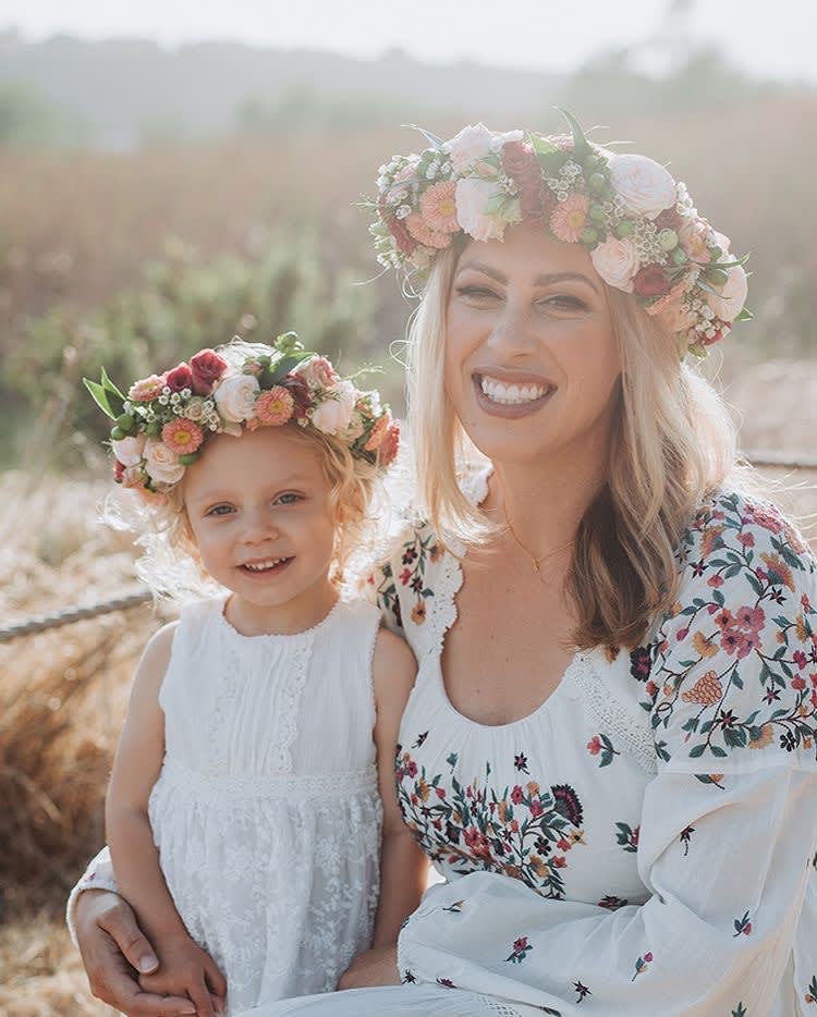 Woman and child wearing floral crowns and white dresses outdoors