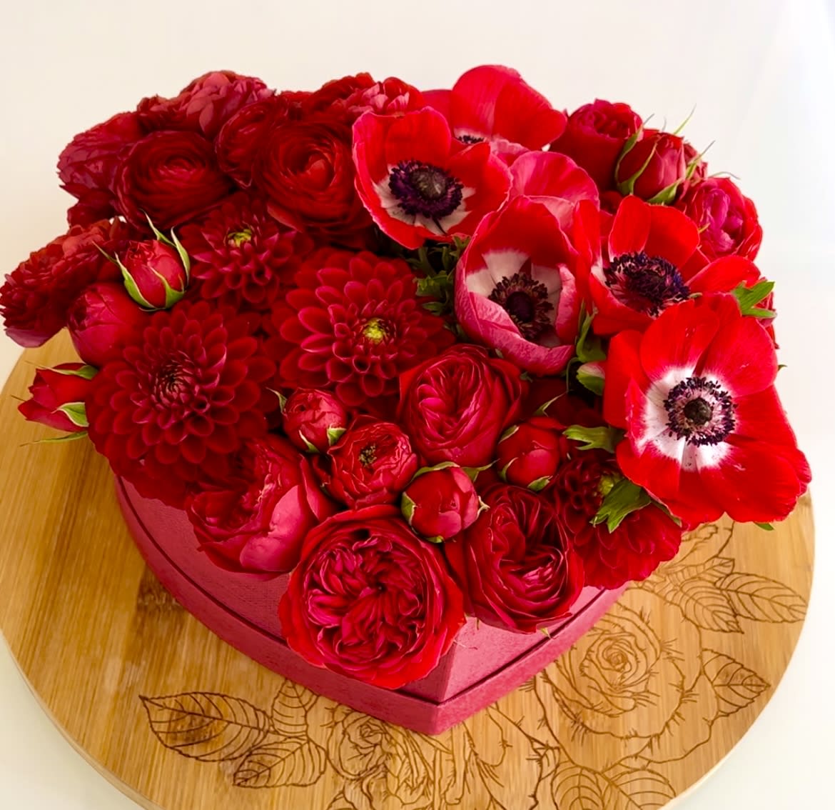 Red floral arrangement in a pink heart-shaped box