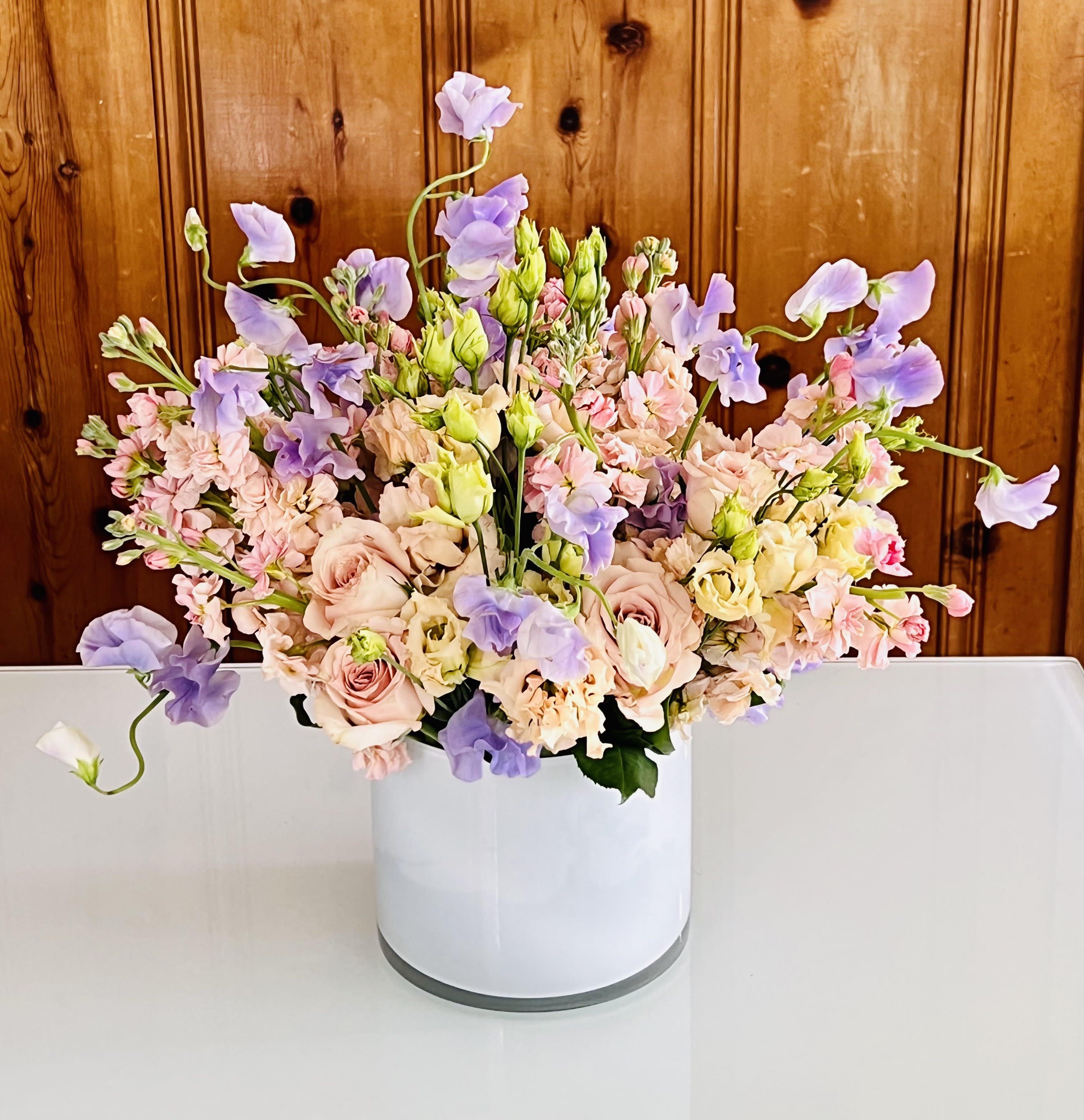 Pastel bouquet of roses, lisianthus, and sweet peas in a white vase