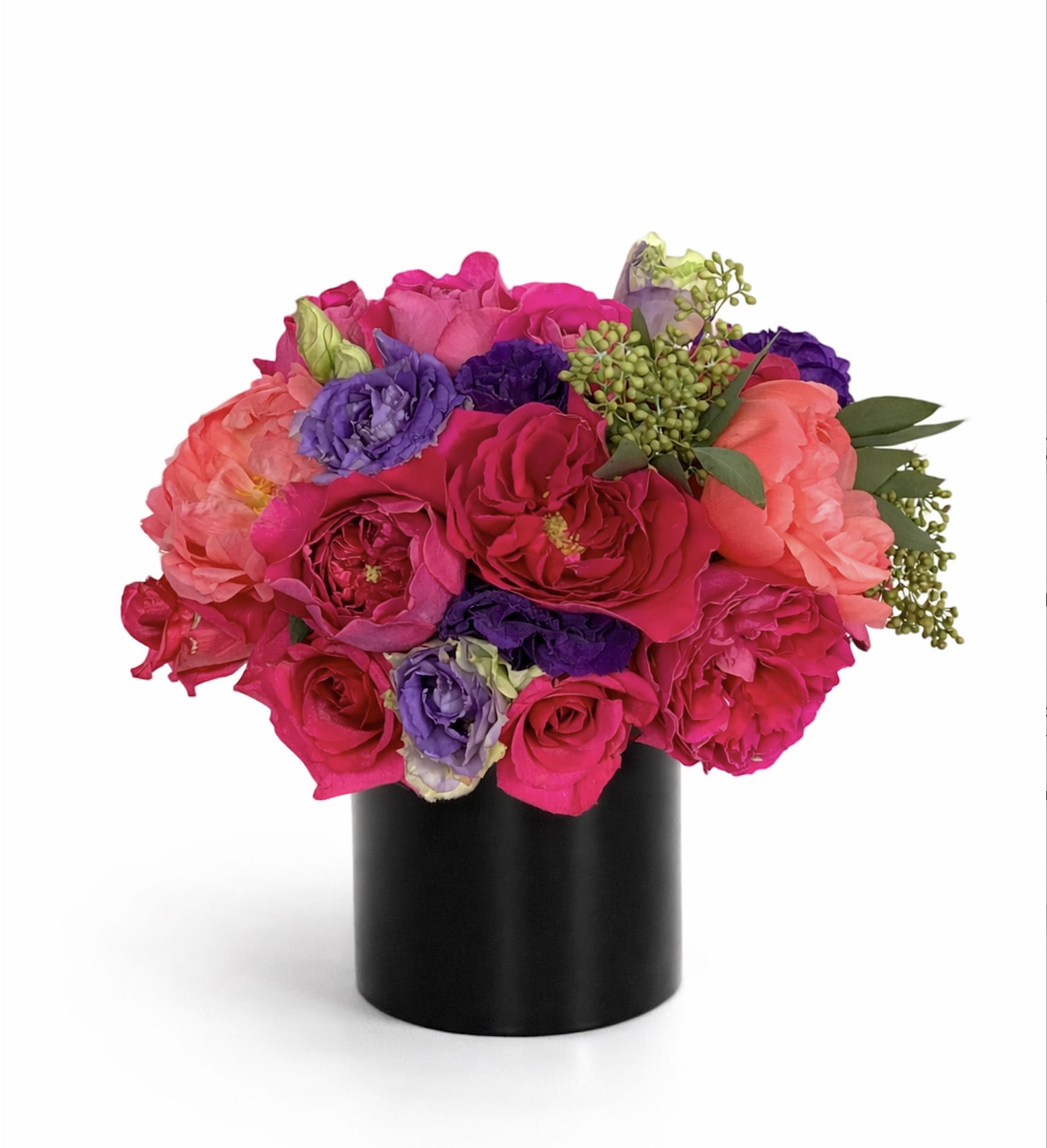 Saturated  - Saturated Elegance  A bold expression of color and artistry, Saturated Elegance is a striking floral composition designed to captivate. Lush garden roses in vivid fuchsia are layered with coral peonies and delicate violet lisianthus, creating a rich interplay of texture and tone. Accented with fresh greenery and sculptural buds, each bloom is thoughtfully placed to achieve a full, dimensional silhouette.  Presented in a sleek black vessel, this arrangement offers a modern contrast that elevates the vibrancy of the florals—making it a true statement piece for any space. Whether gifted or styled in your home, it evokes confidence, celebration, and refined taste.  Perfect for birthdays, celebrations, or moments that call for something unforgettable, Saturated Elegance is designed for those who appreciate bold beauty and elevated design.