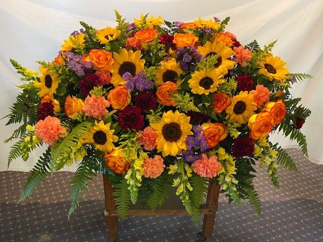 Large mixed flower arrangement with sunflowers, orange roses, and carnations
