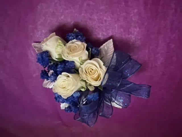 Bouquet of cream roses with blue filler and a dark ribbon