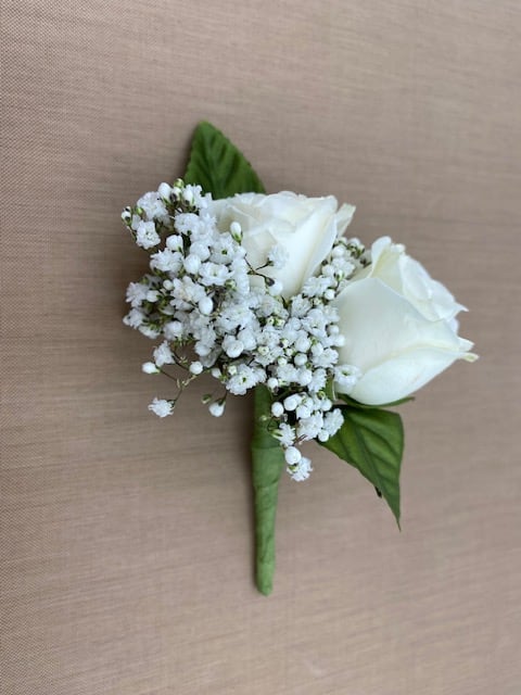 White rose boutonniere with baby's breath and green leaves