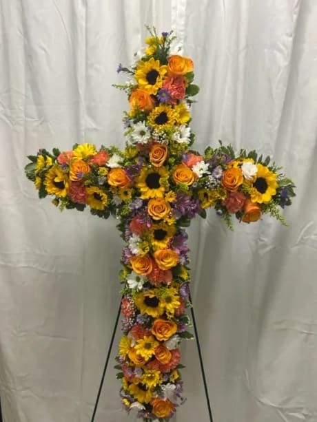 Cross-shaped floral tribute with sunflowers, orange roses, and mixed blooms
