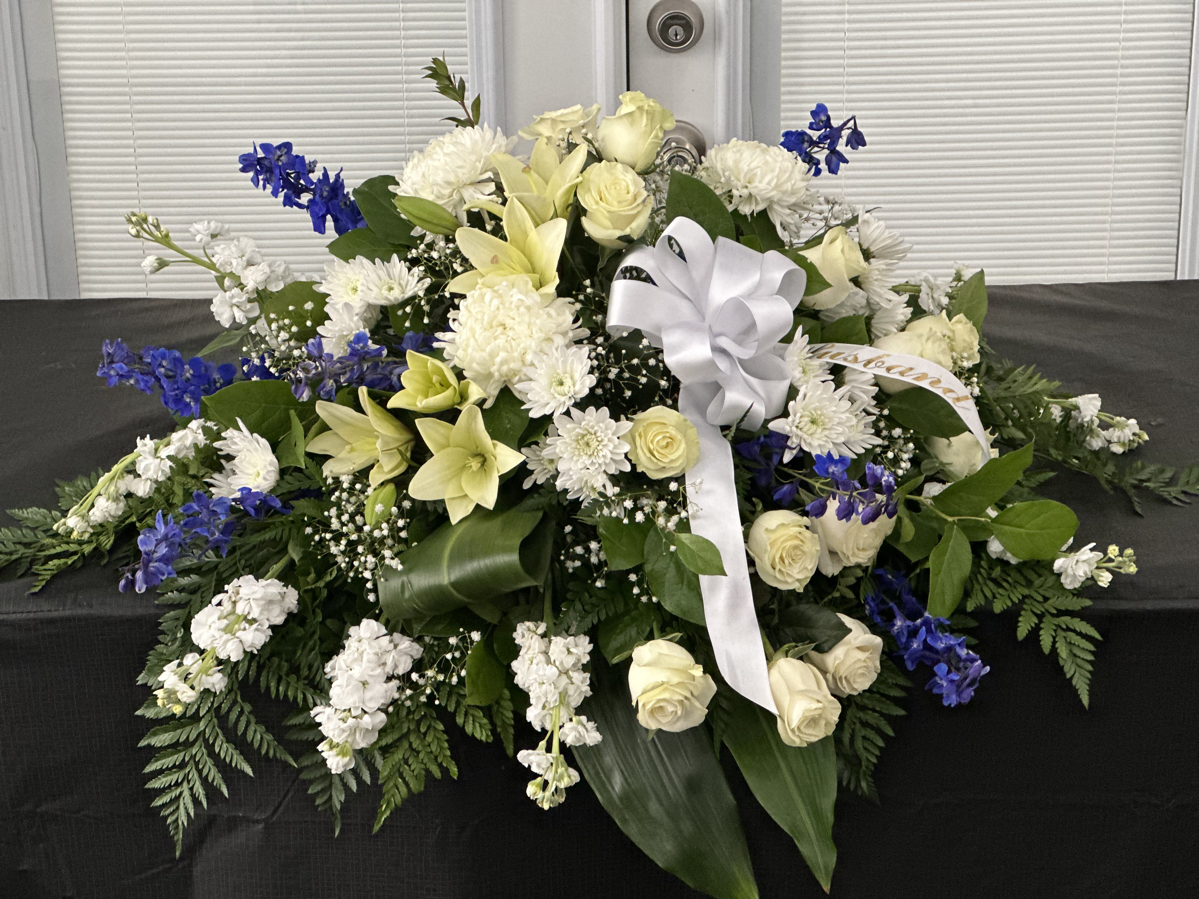 Large white and blue floral spray with a white ribbon bow