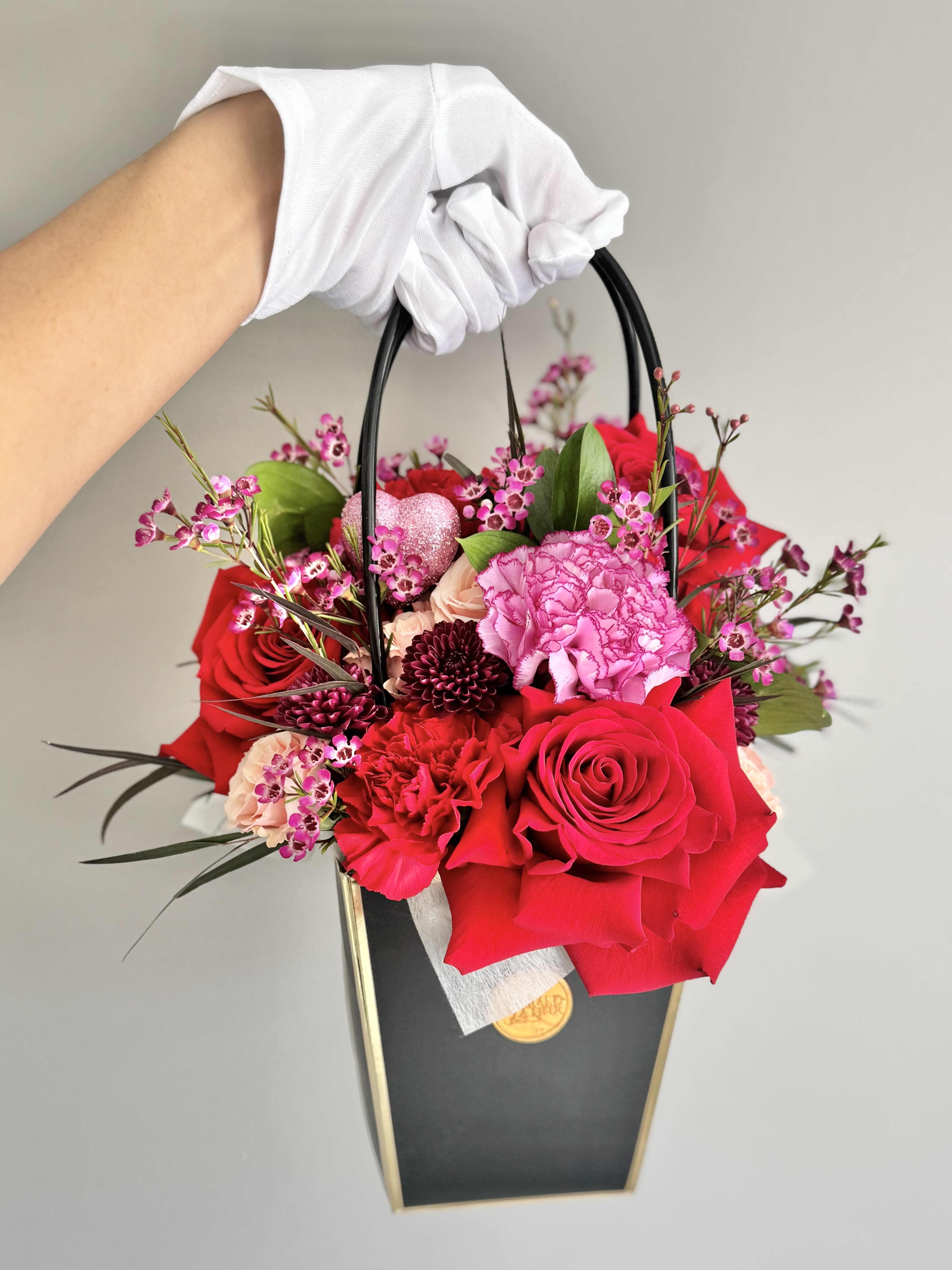 Handheld floral gift bag with red and pink roses and carnations