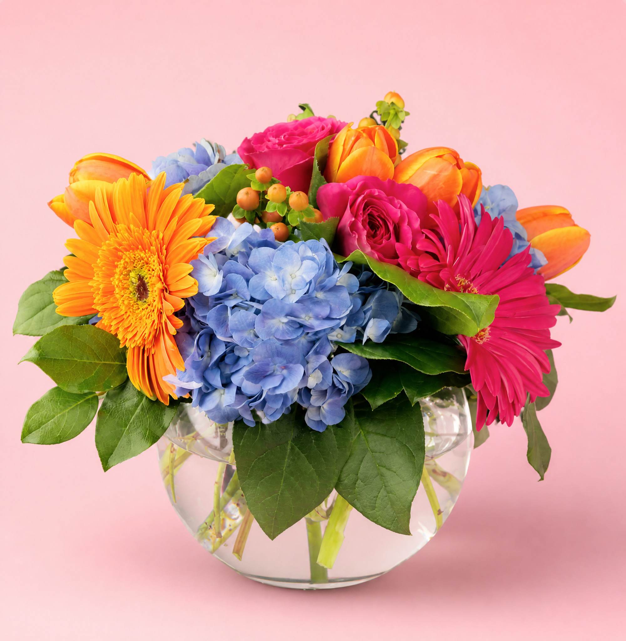 Colorful mixed bouquet in a clear glass vase with blue hydrangeas and bright gerberas