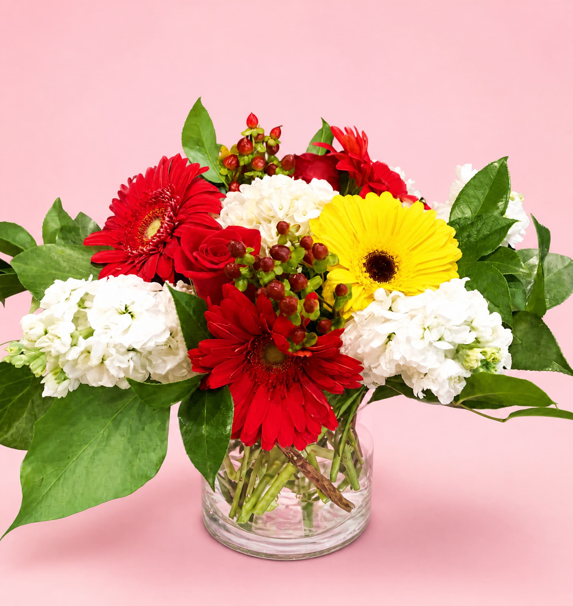 Mixed bouquet of red, yellow, and white flowers in a clear glass vase