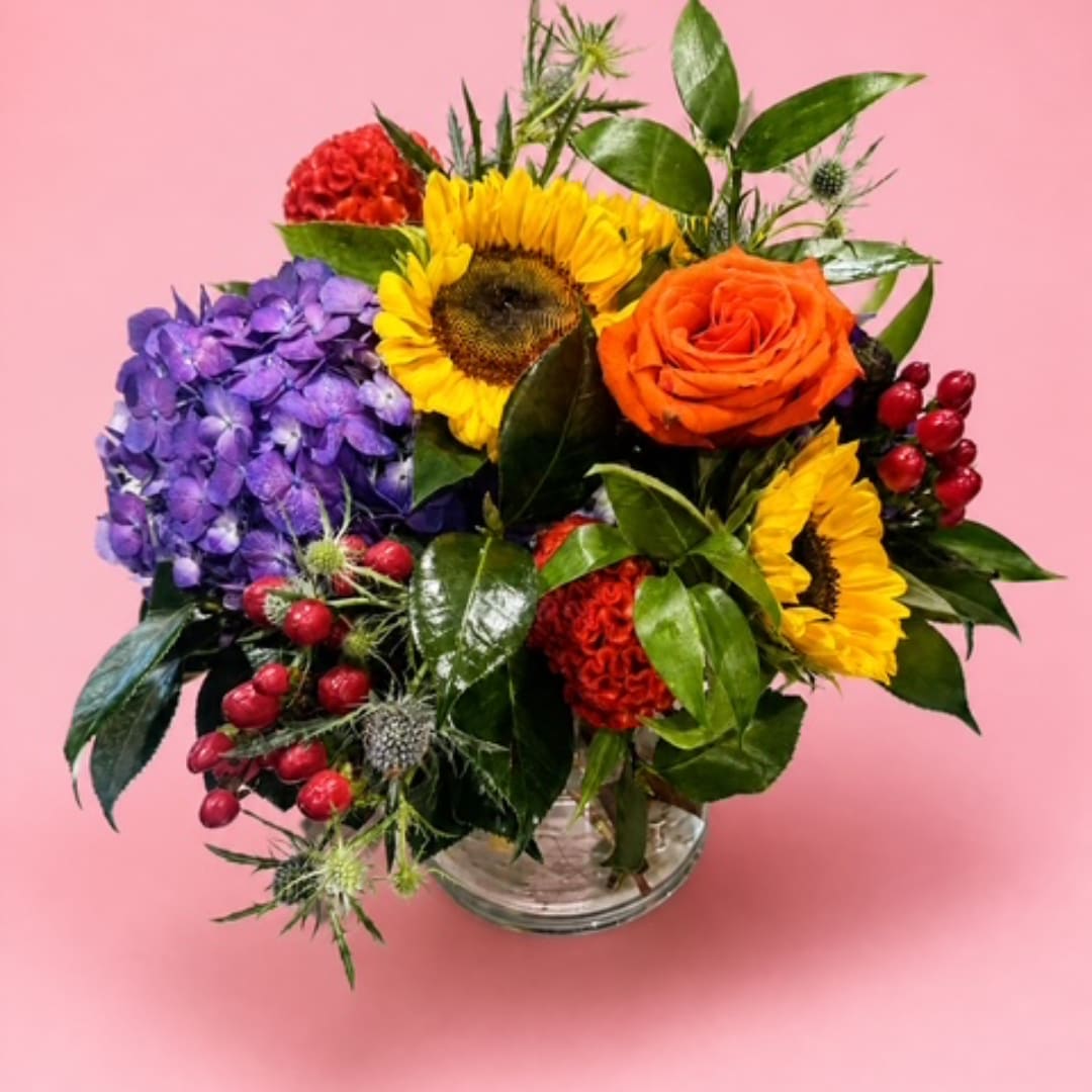 Colorful bouquet with sunflowers, roses, and hydrangea in a glass vase