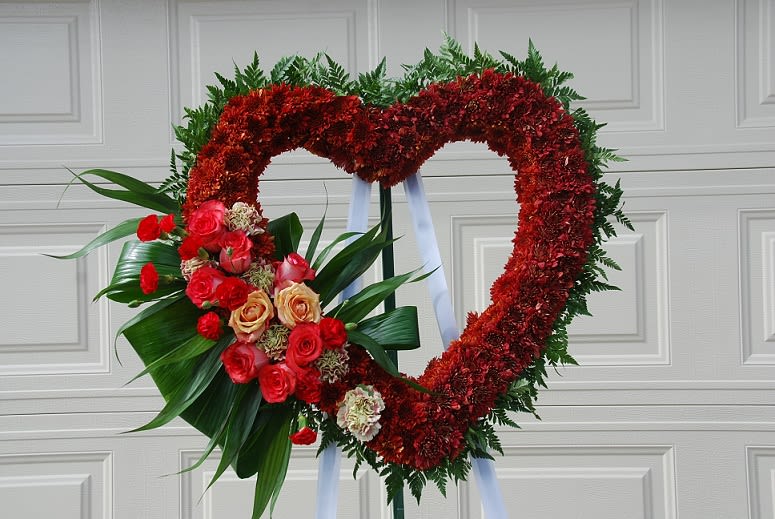 Open Heart - An open heart sympathy arrangement filled with burgundy chrysanthemums. A side accent spray with red mini carnations, and roses.