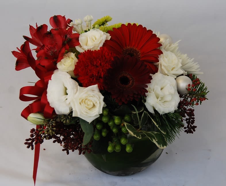 Joyful Vase  - A vase of red gerbera daisies, red carnations, alstroemerias, white lisianthus, roses, green button pom poms, and green hypericum with evergreens in  Christmas Arrangement Centerpiece.