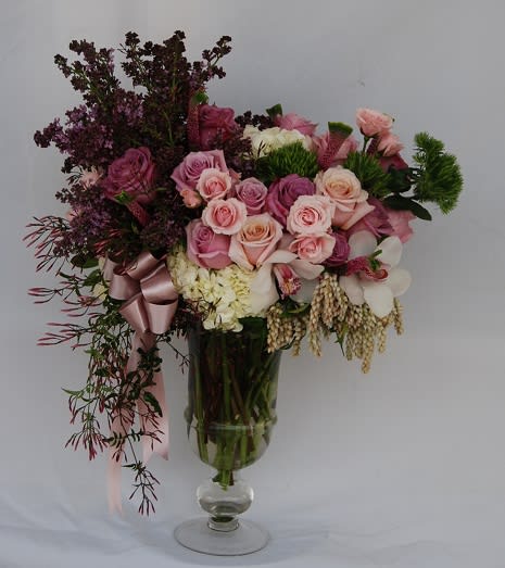 Pink and white rose bouquet in a clear glass vase with a ribbon