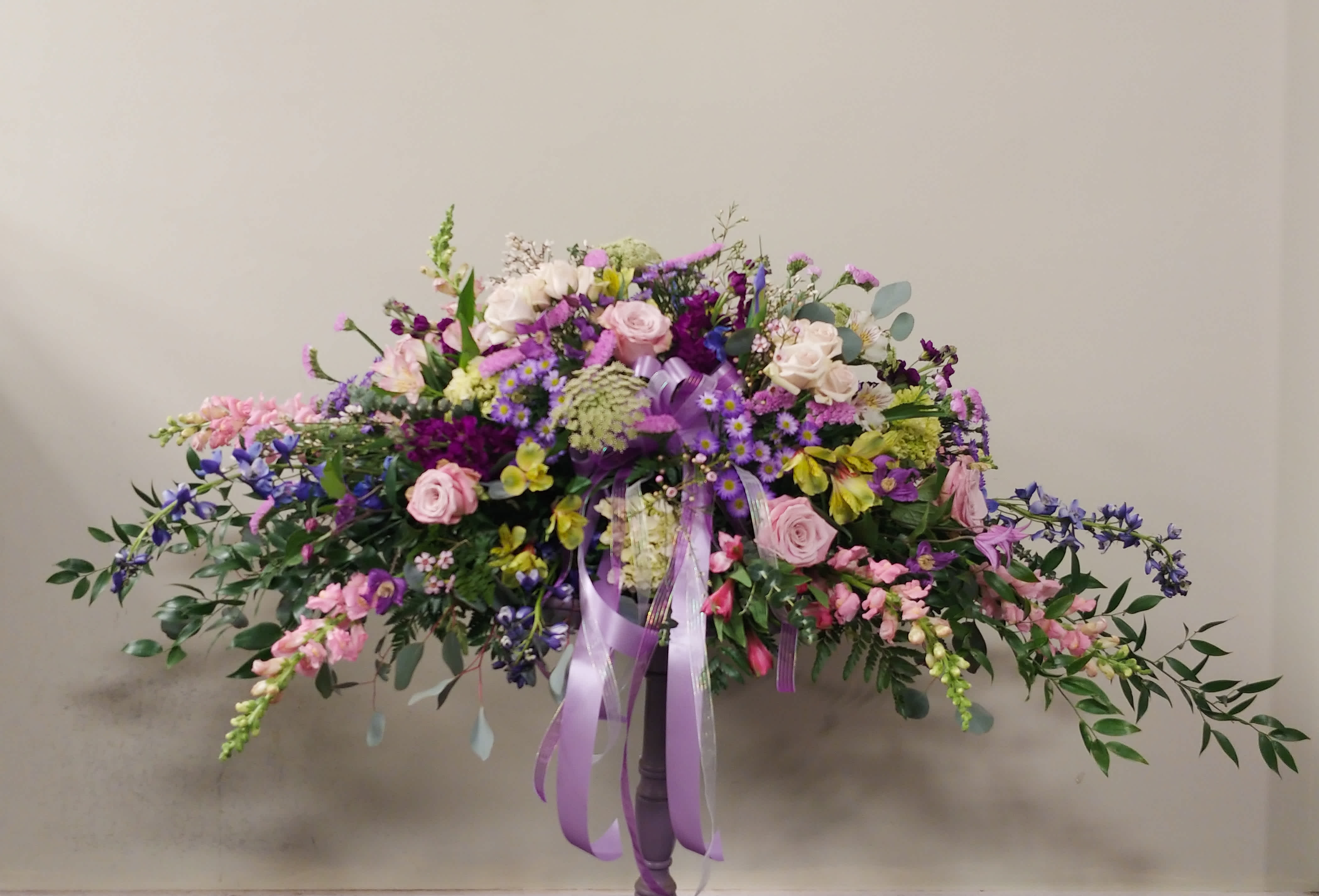 Large pastel floral arrangement in a pedestal vase with trailing blooms
