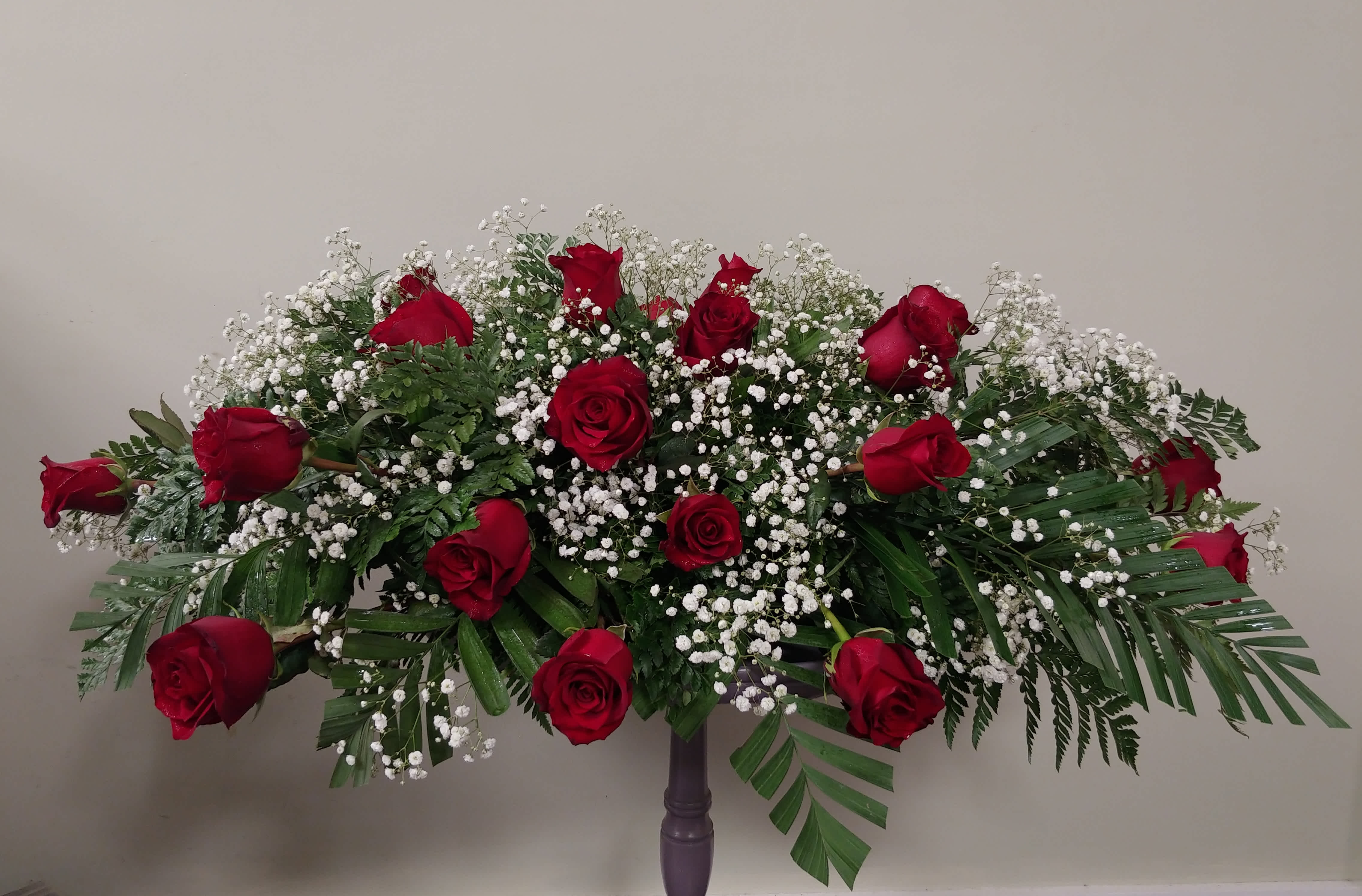 Large red rose arrangement with white baby's breath on a stand