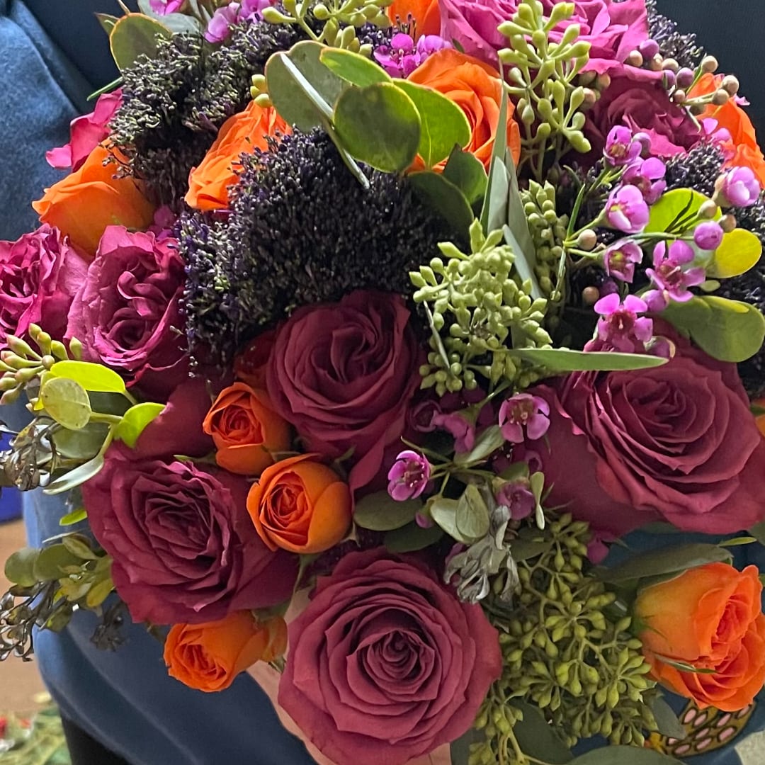 Bouquet of purple and orange roses with small purple filler flowers
