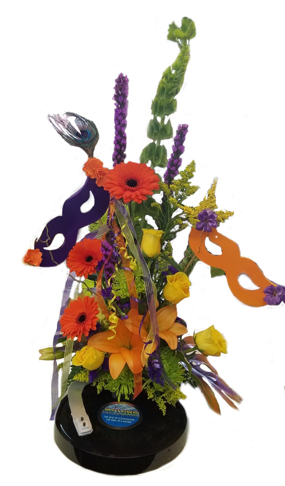 Bright mixed flower arrangement with masks and ribbons on a black base
