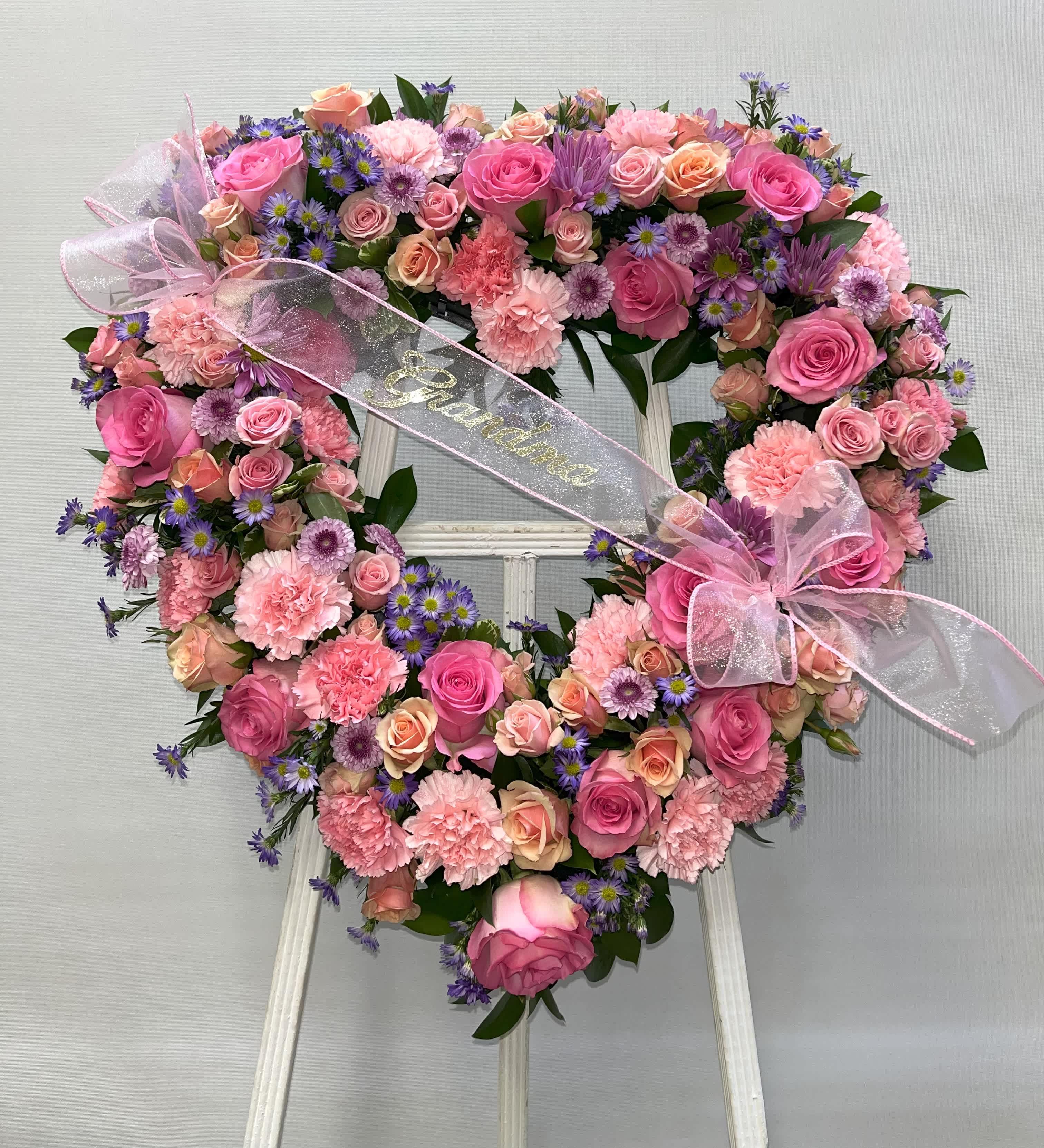 Heart-shaped floral wreath with pink roses, carnations, and purple daisies