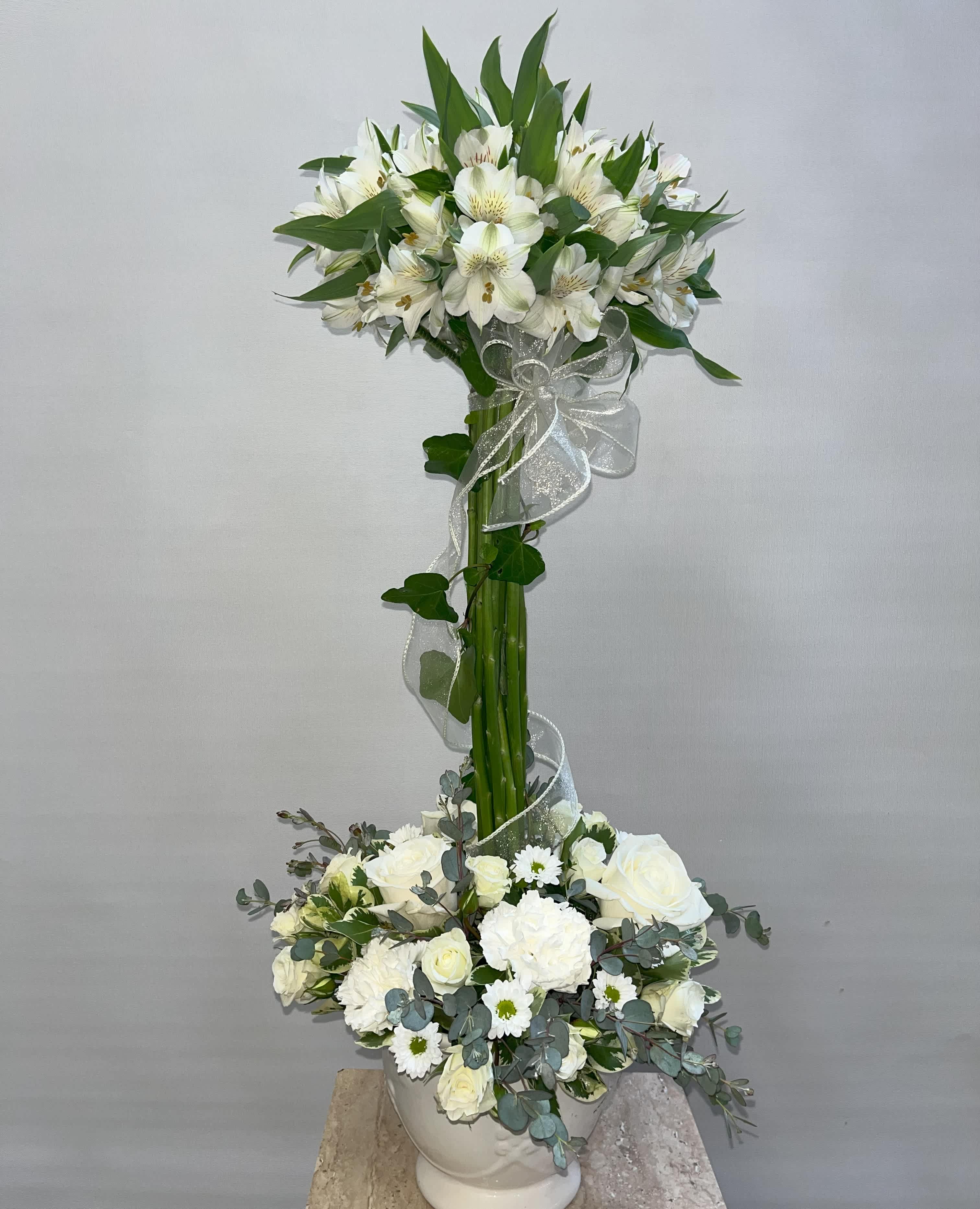 Tall white floral arrangement with a lower white bouquet in a vase