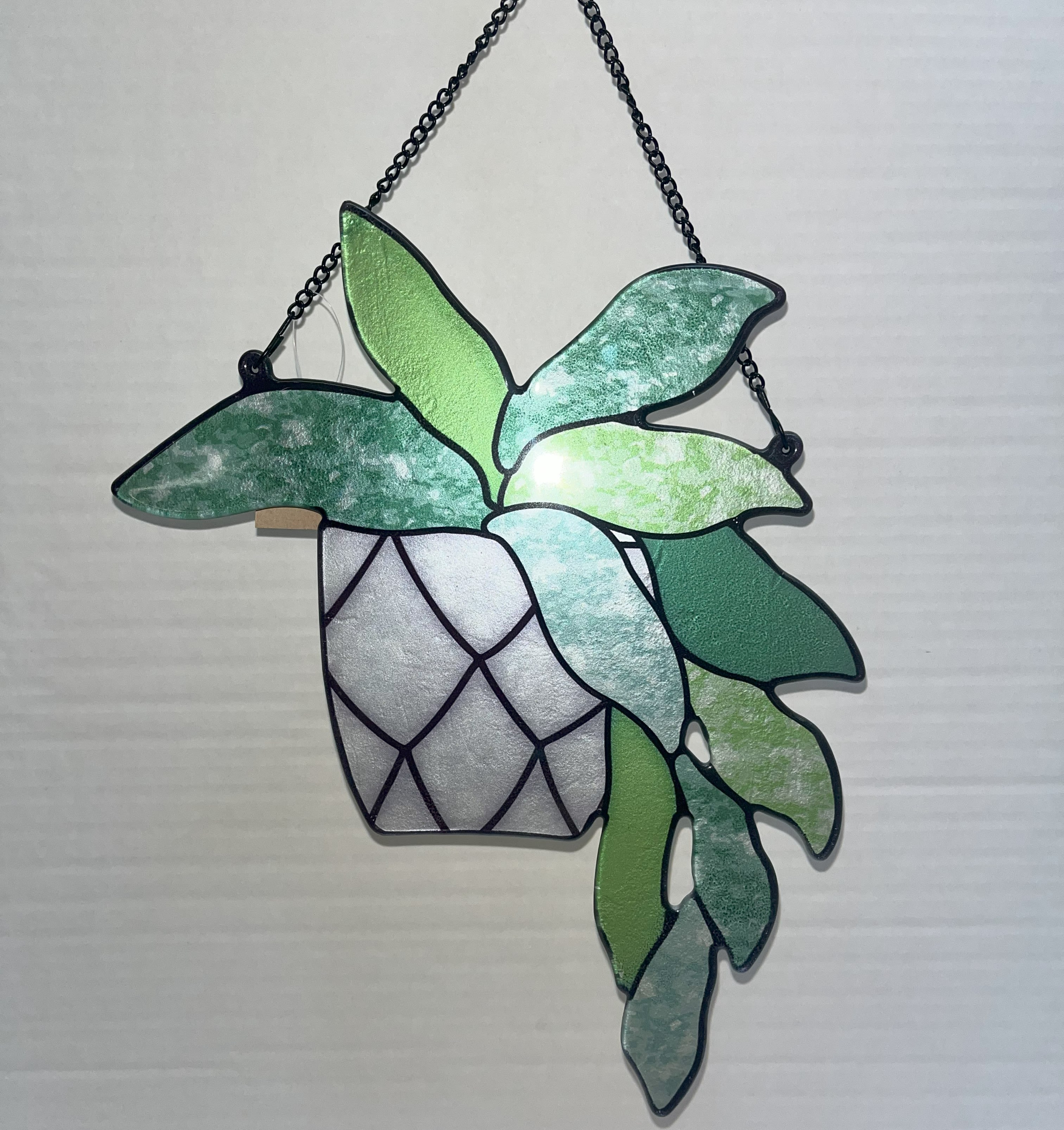 Hanging stained-glass plant with green leaves in a black metal frame