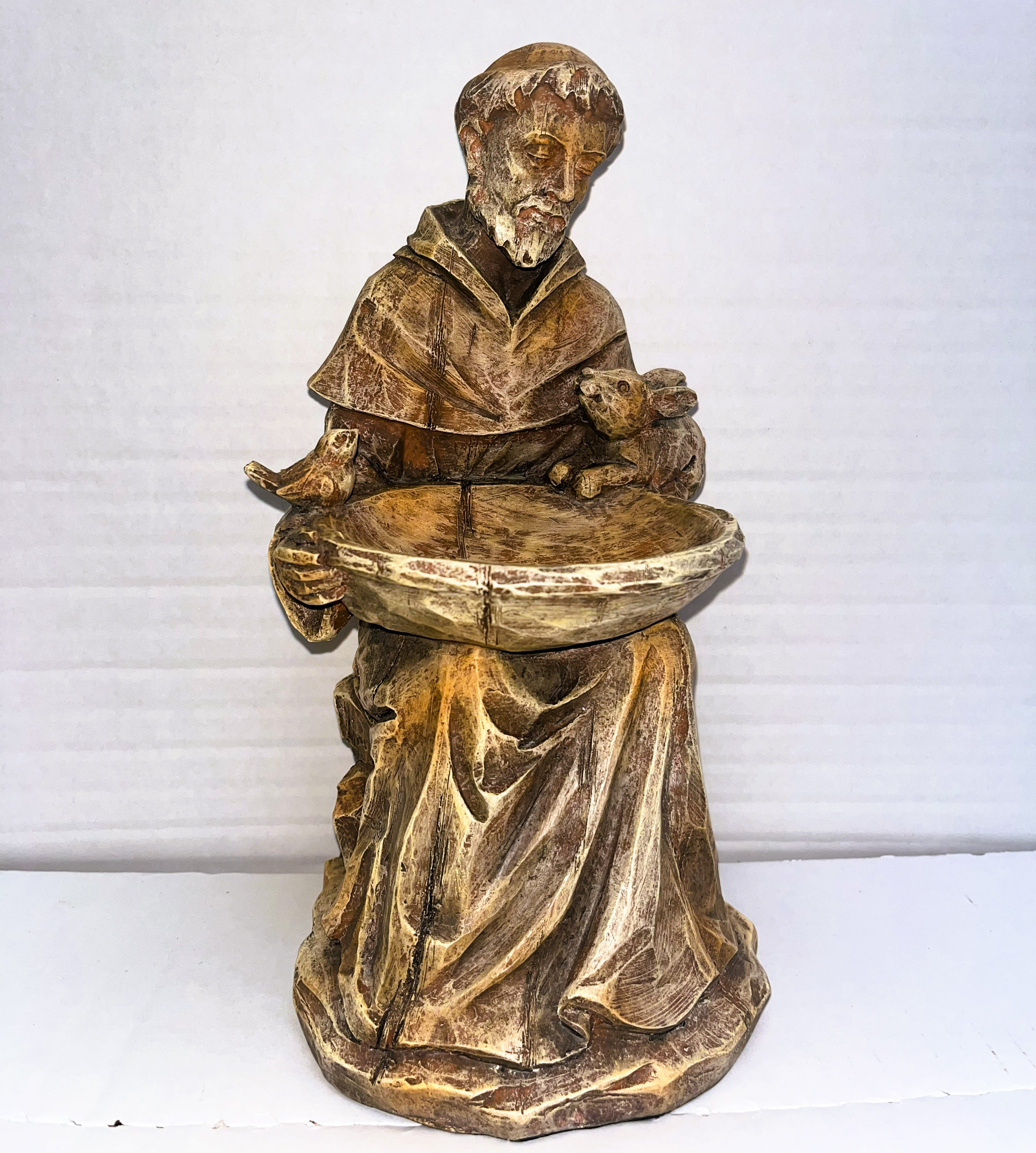 Wooden monk statue holding a shallow bowl with a bird and rabbit
