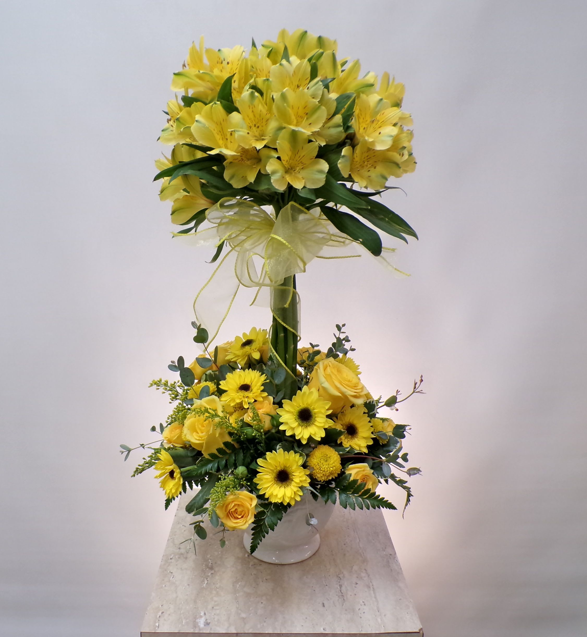 Yellow floral arrangement with roses and daisies in a white vase