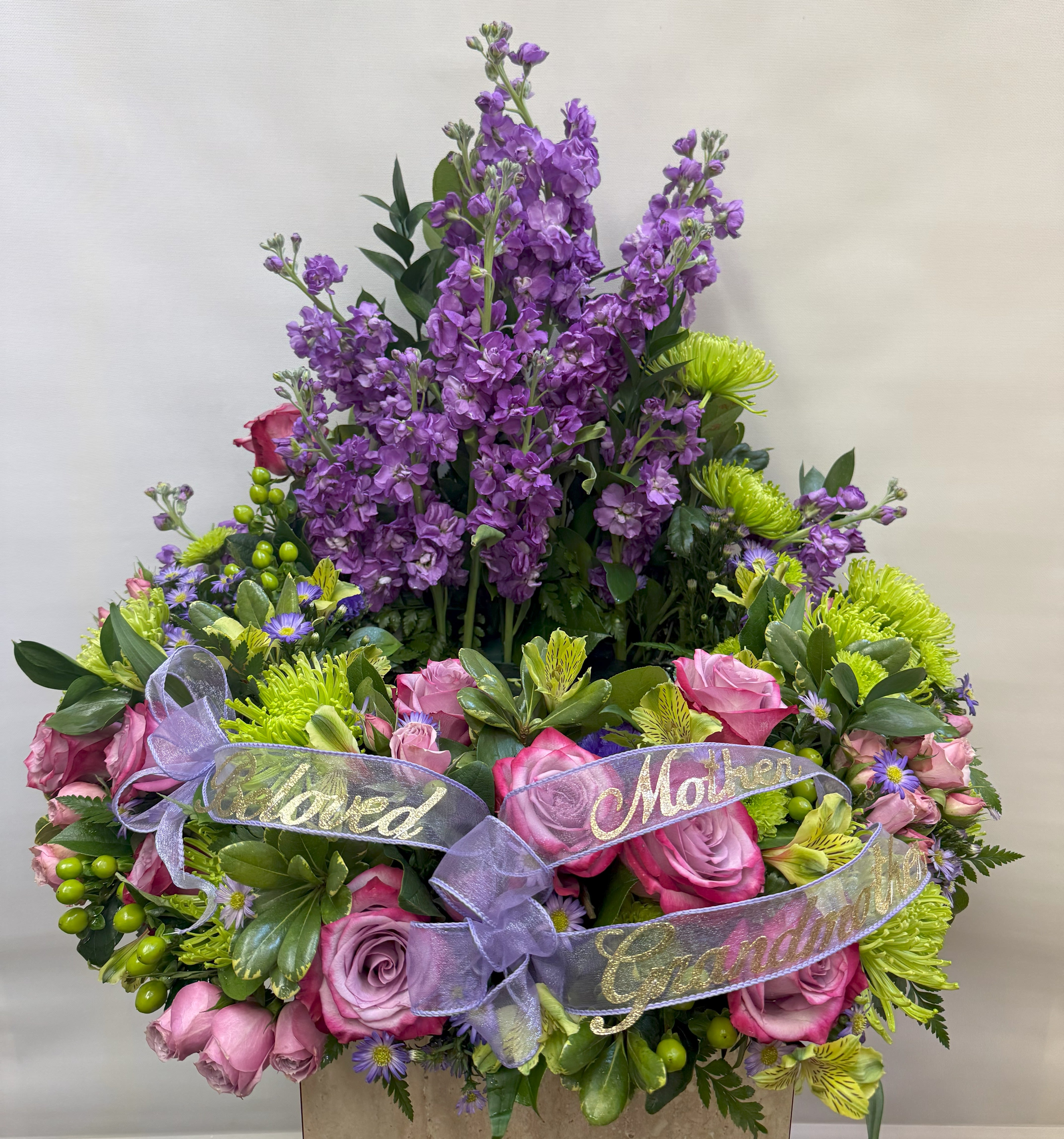 Purple and pink floral arrangement with ribbon labels for family members