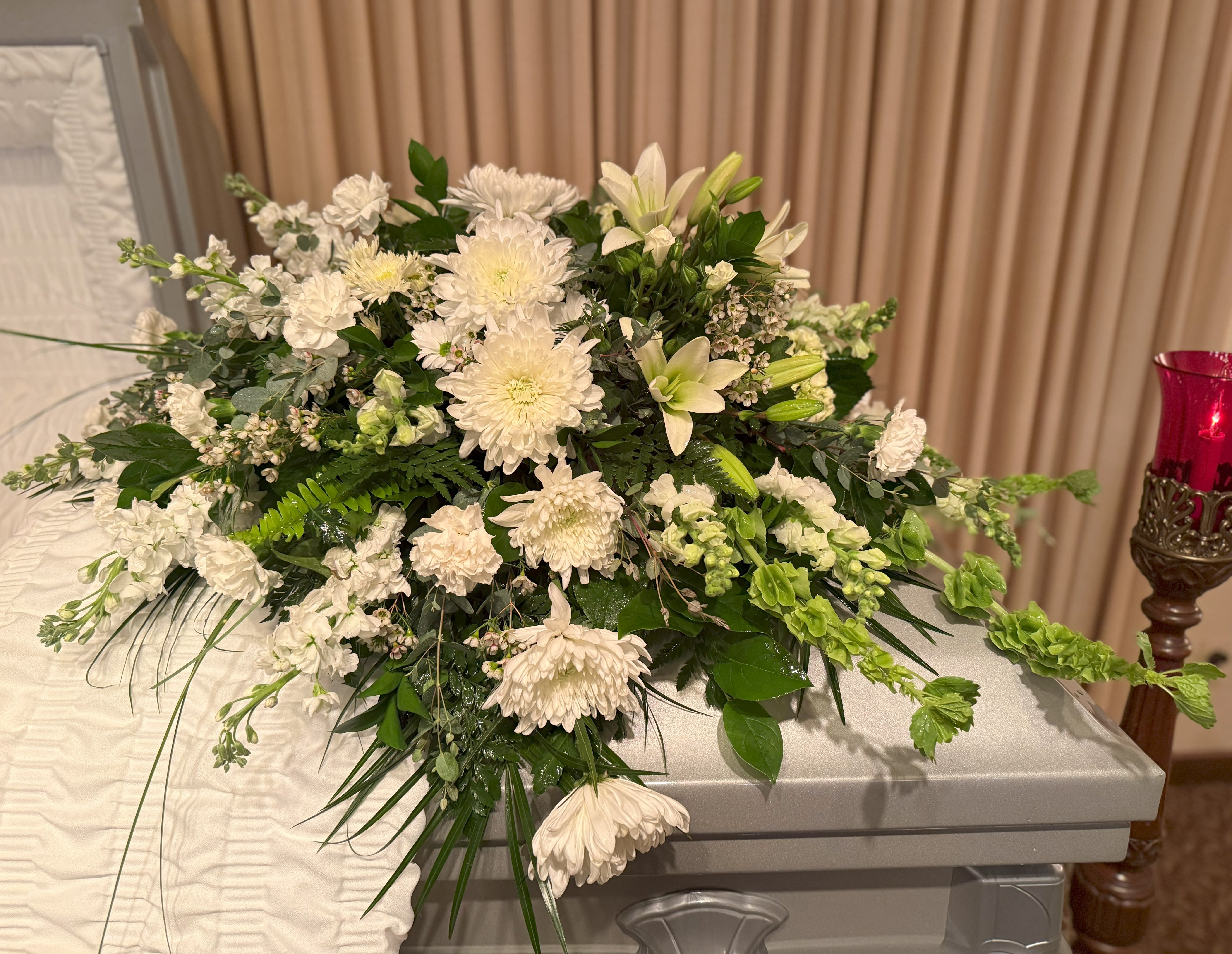 Large white floral spray on a casket with green foliage