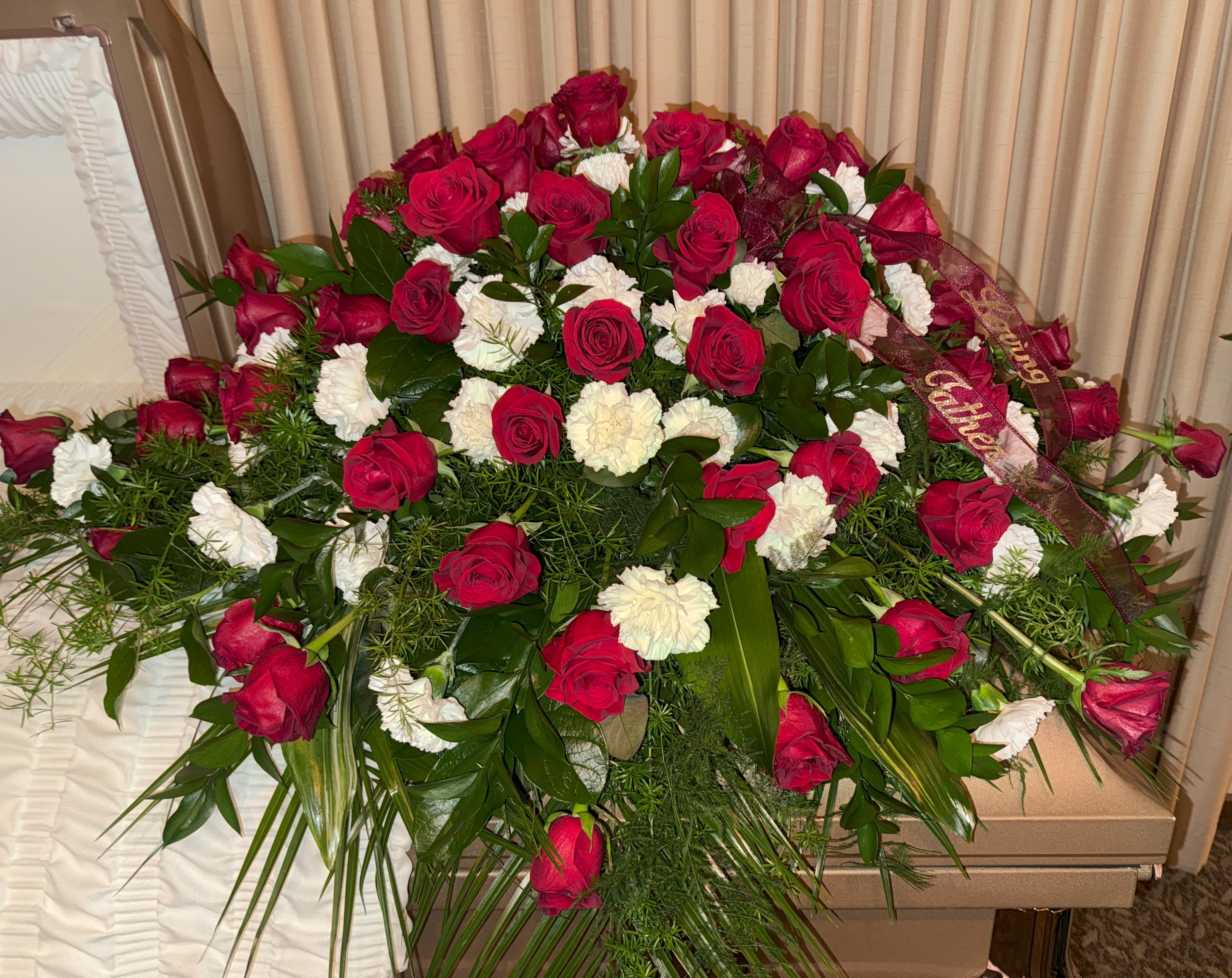Large red rose and white carnation funeral spray with ribbon