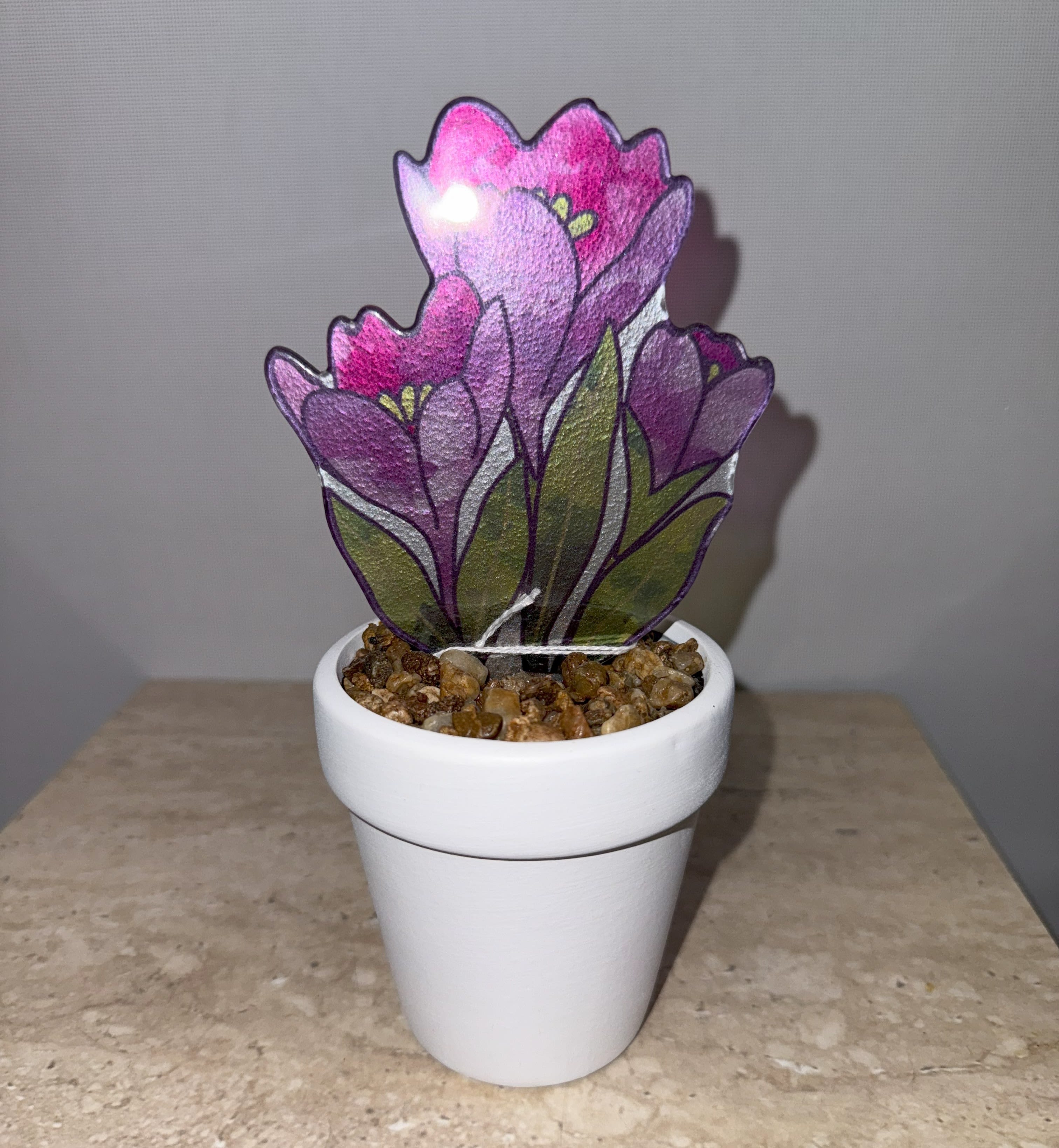Purple flower-shaped decorative plant in a white pot with pebbles