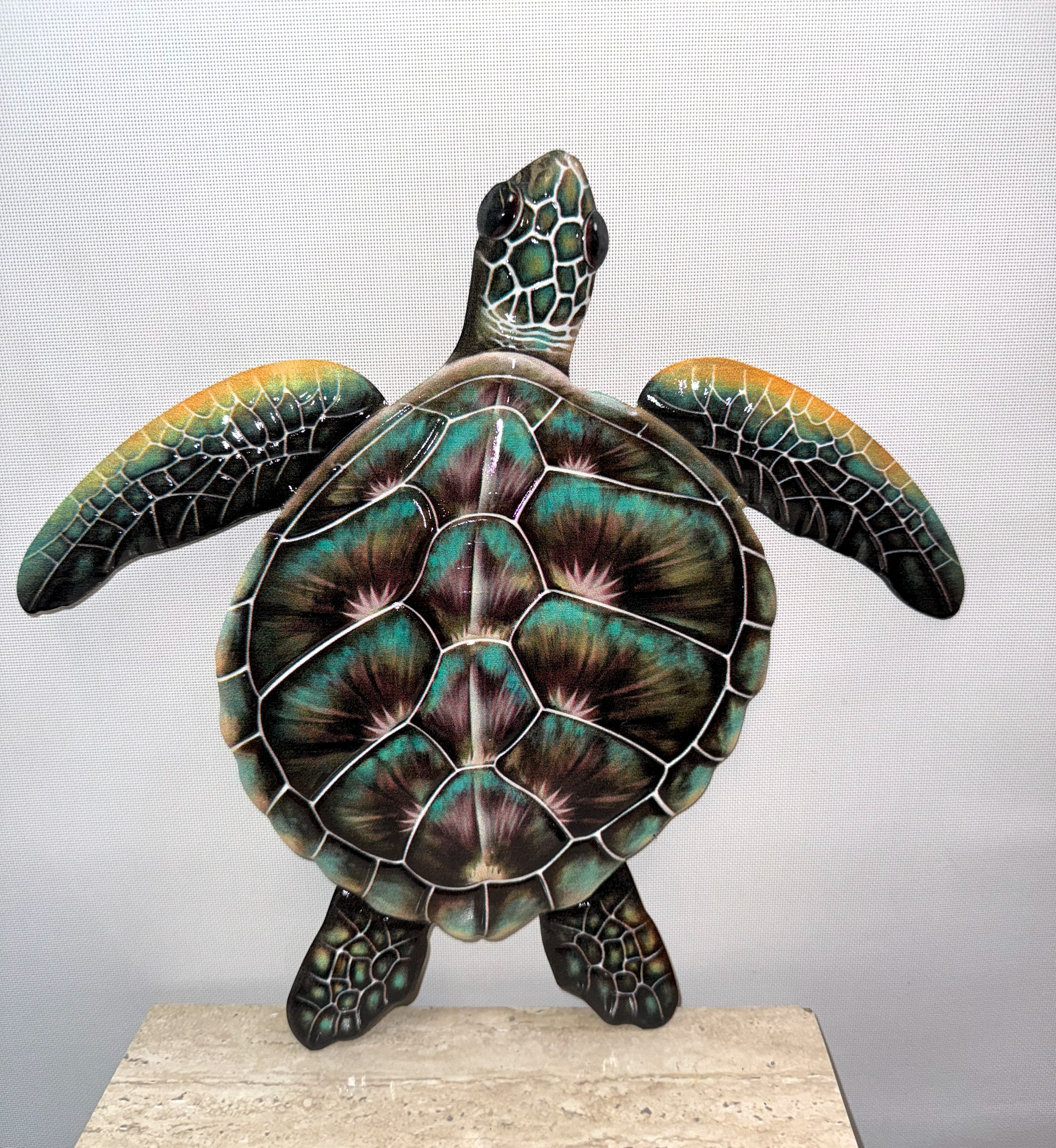 Decorative turtle sculpture with iridescent shell on a stone base