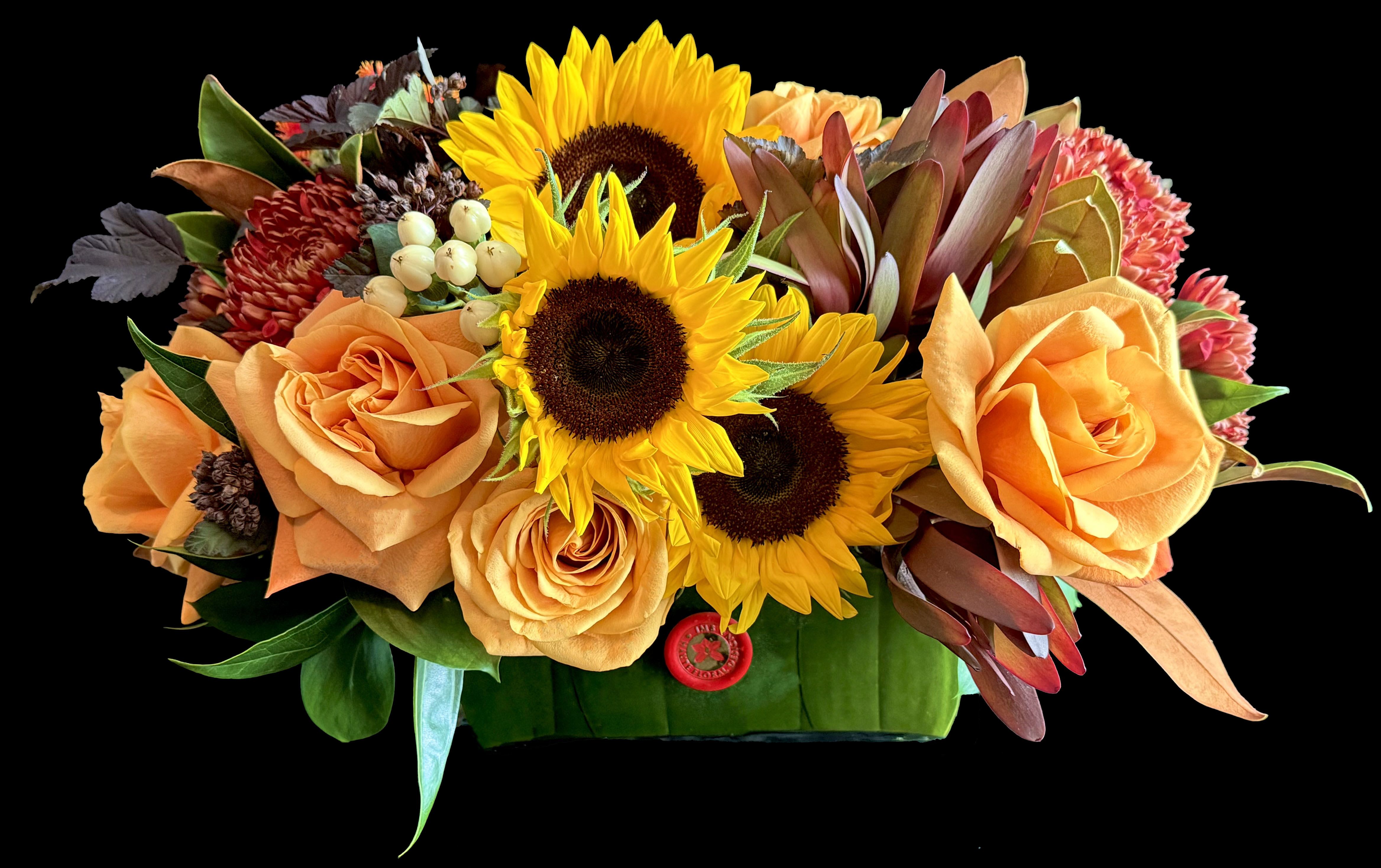Orange roses and sunflowers arranged in a low rectangular container