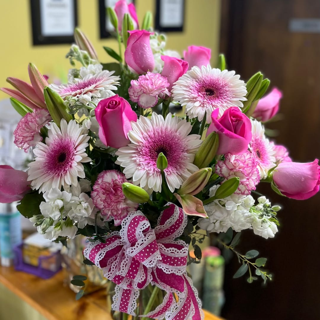 Pink and white mixed bouquet with roses, daisies, and lilies tied with a ribbon
