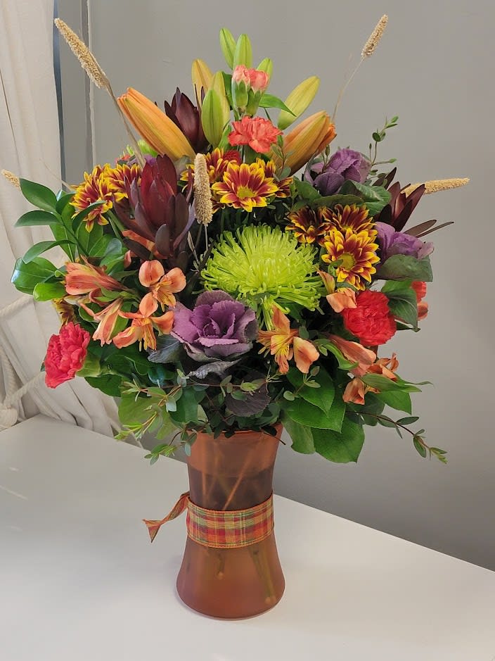 Mixed bouquet in a copper vase with orange, purple, and green flowers