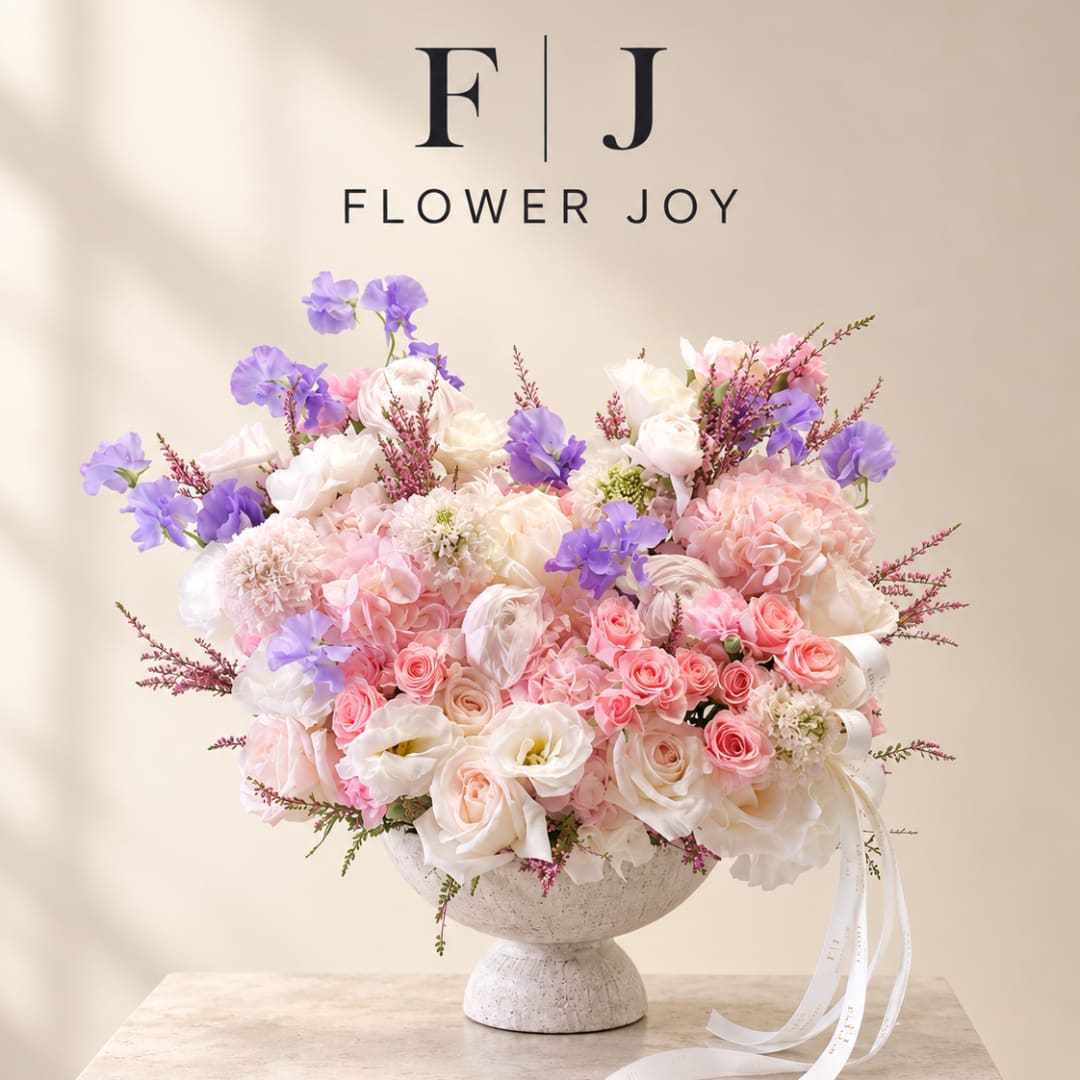 Pink and white floral arrangement with purple accents in a pedestal vase