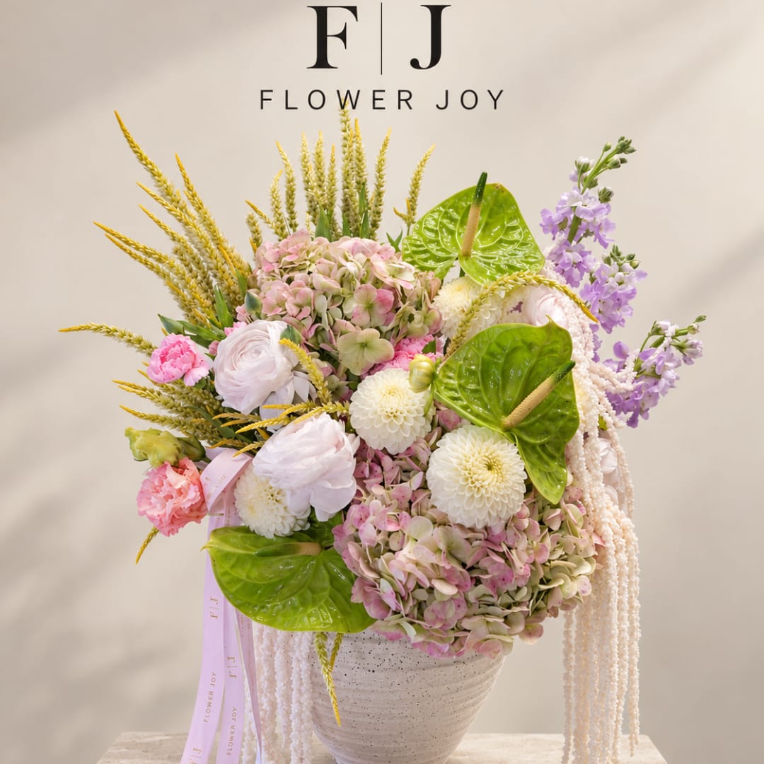 Pastel floral arrangement in a white vase with pink, white, and purple blooms.