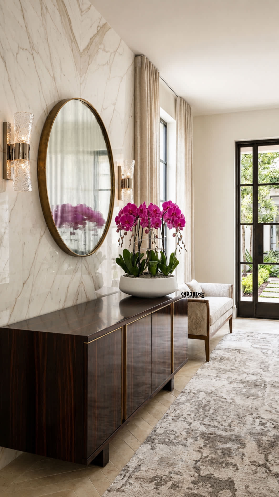 Pink orchid arrangement in a white bowl on a dark console table